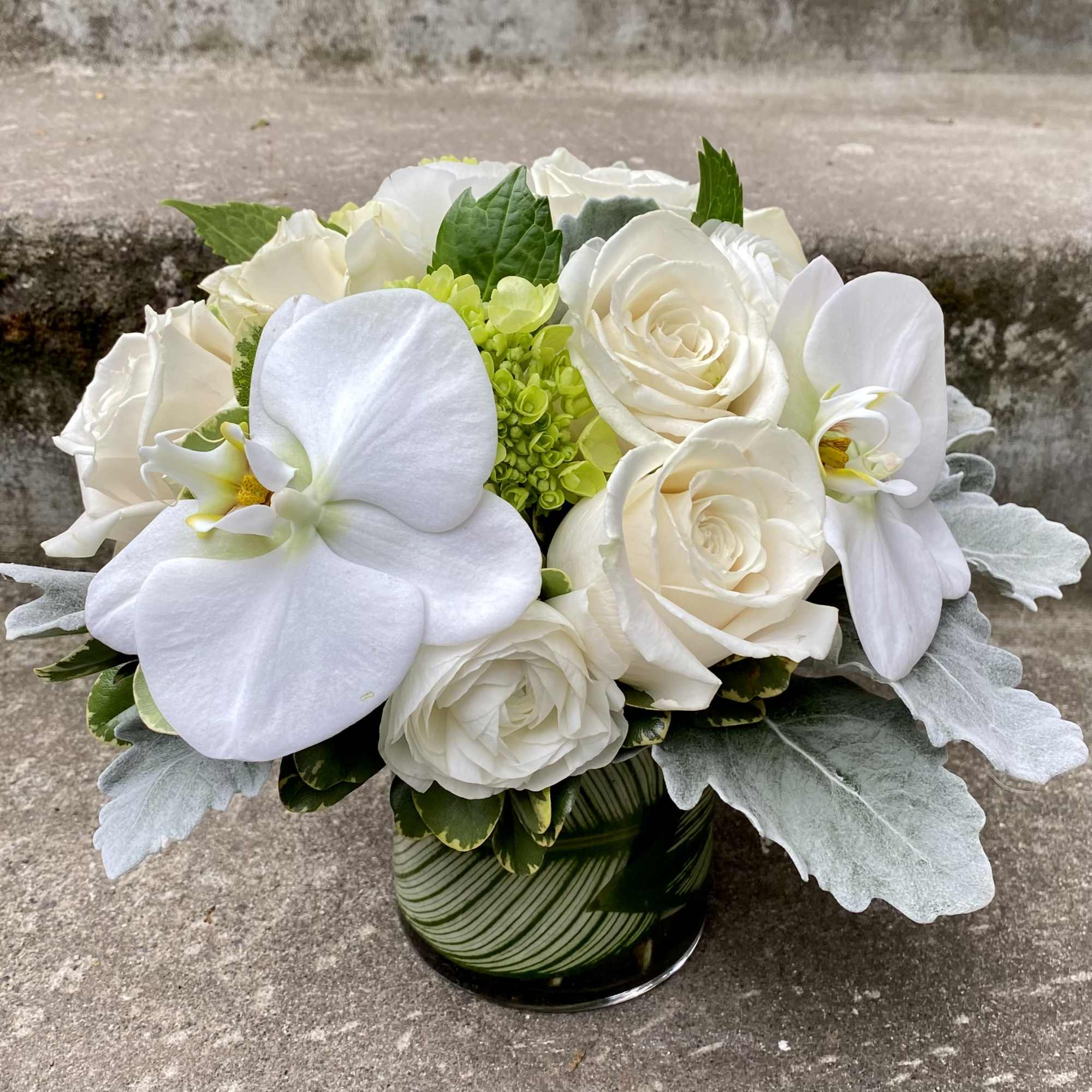 White roses and orchids arranged in a glass vase