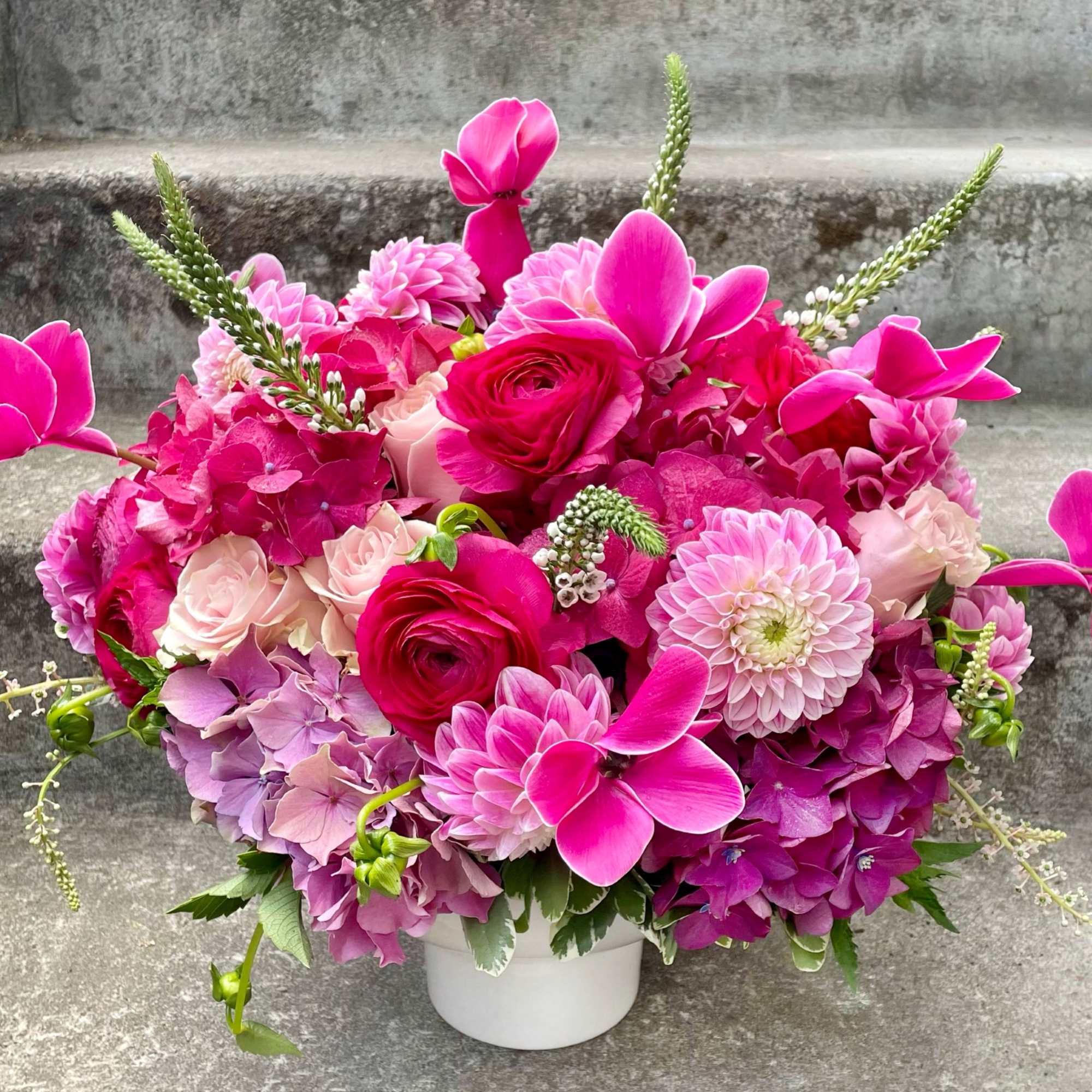 Bright pink floral arrangement in a white vase