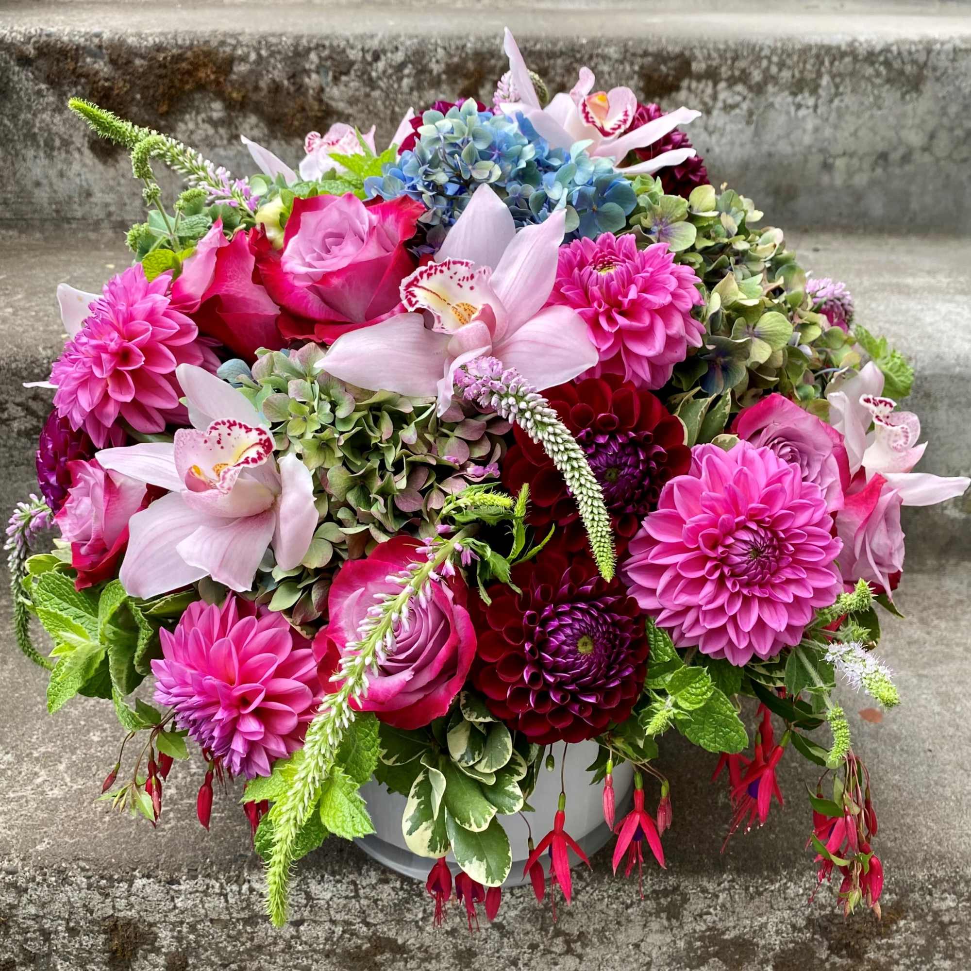 Colorful bouquet of pink, purple, and blue flowers in a white container
