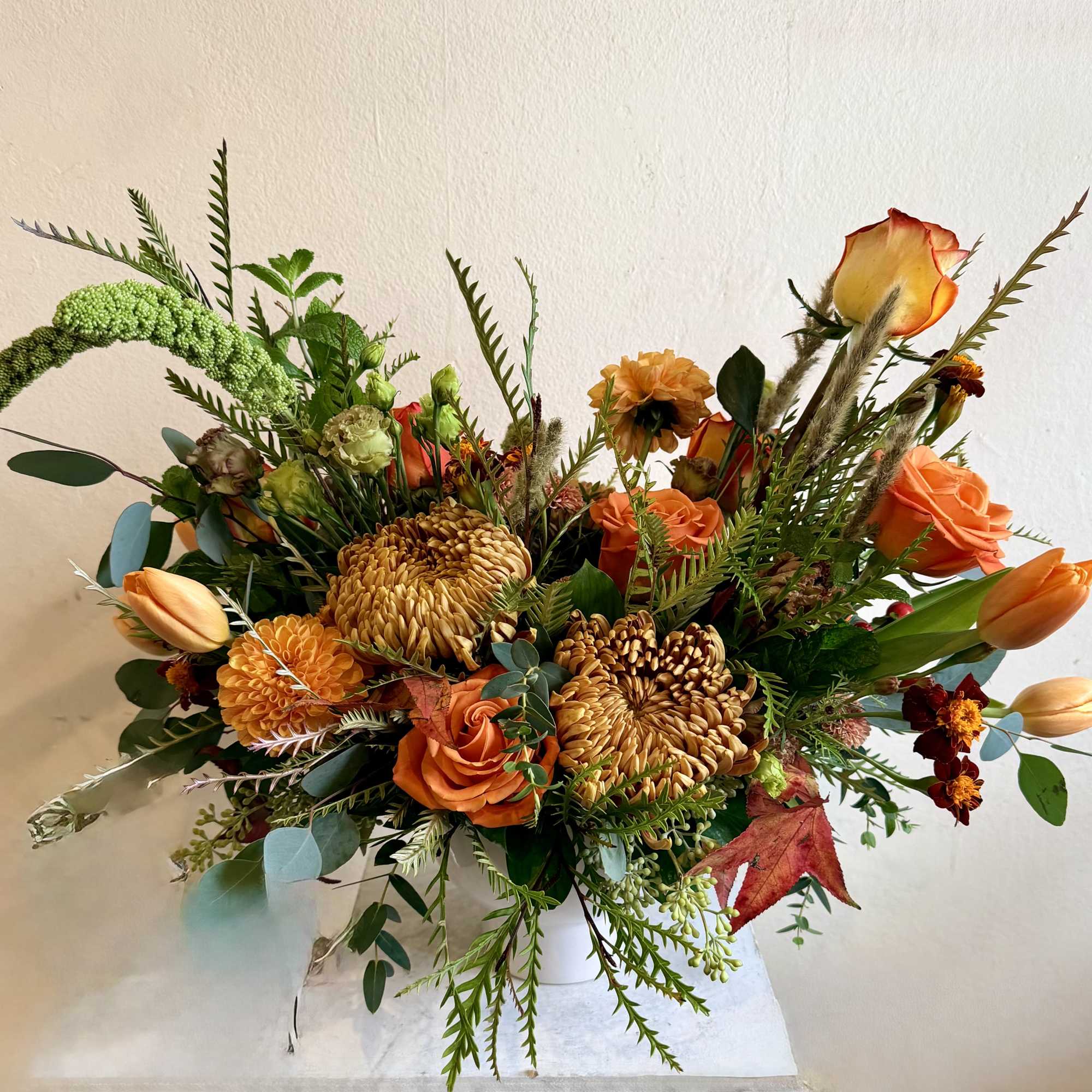 Orange and gold mixed bouquet in a white vase