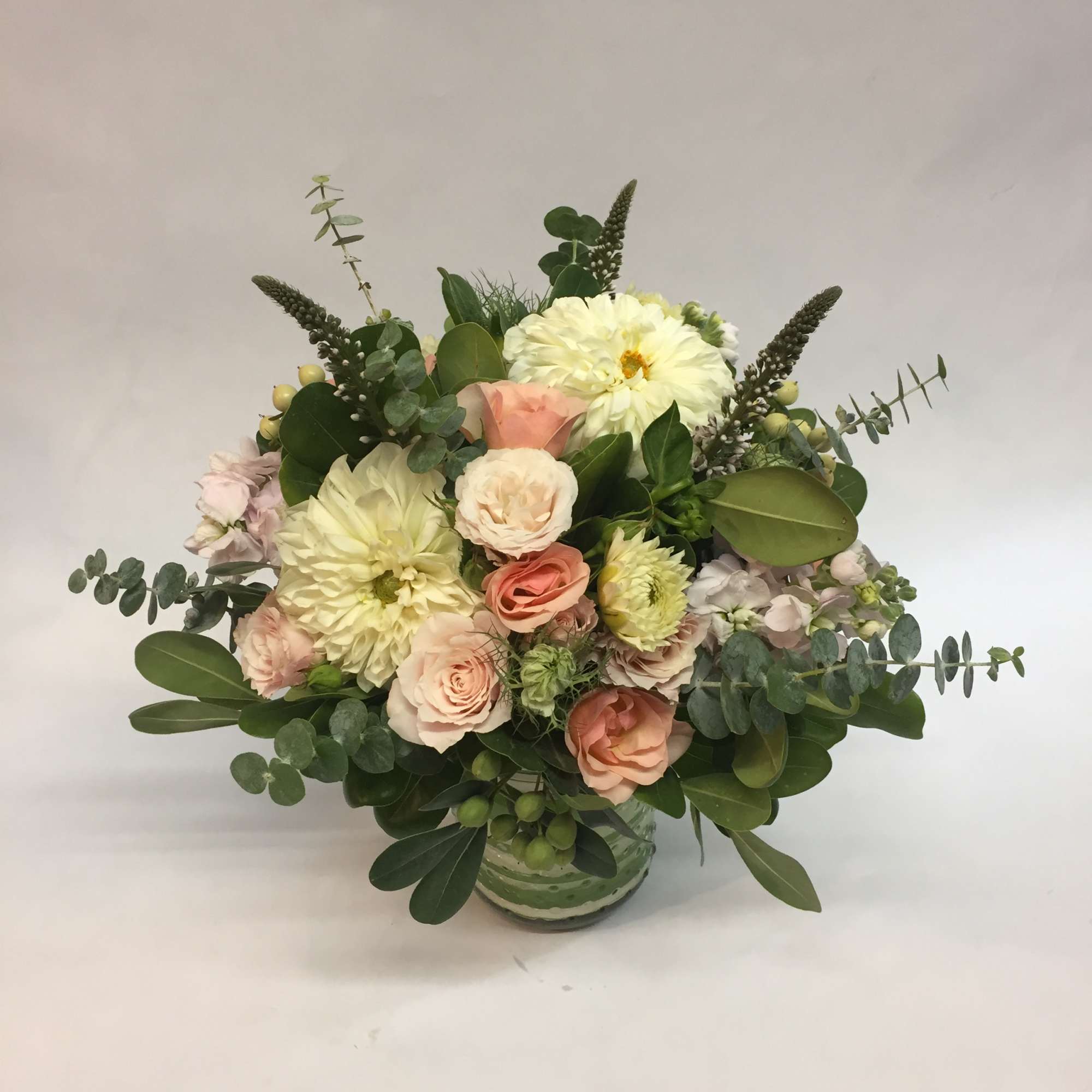 Mixed bouquet of pale pink and cream flowers in a glass vase