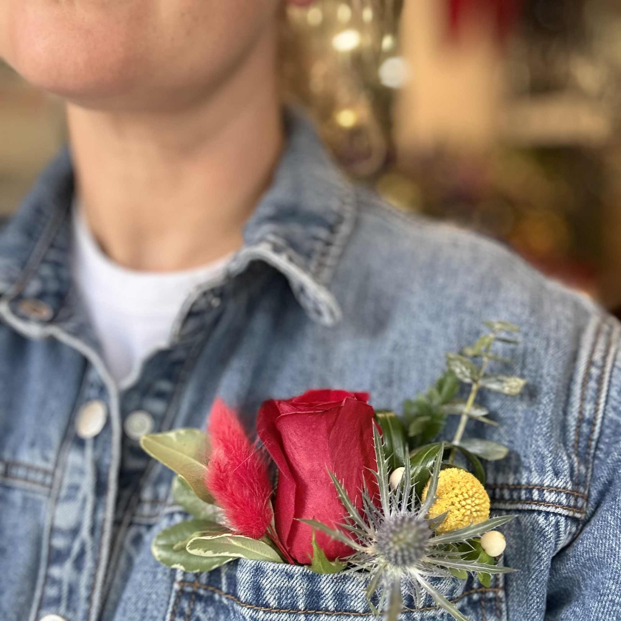 Red rose boutonniere pinned to a denim jacket