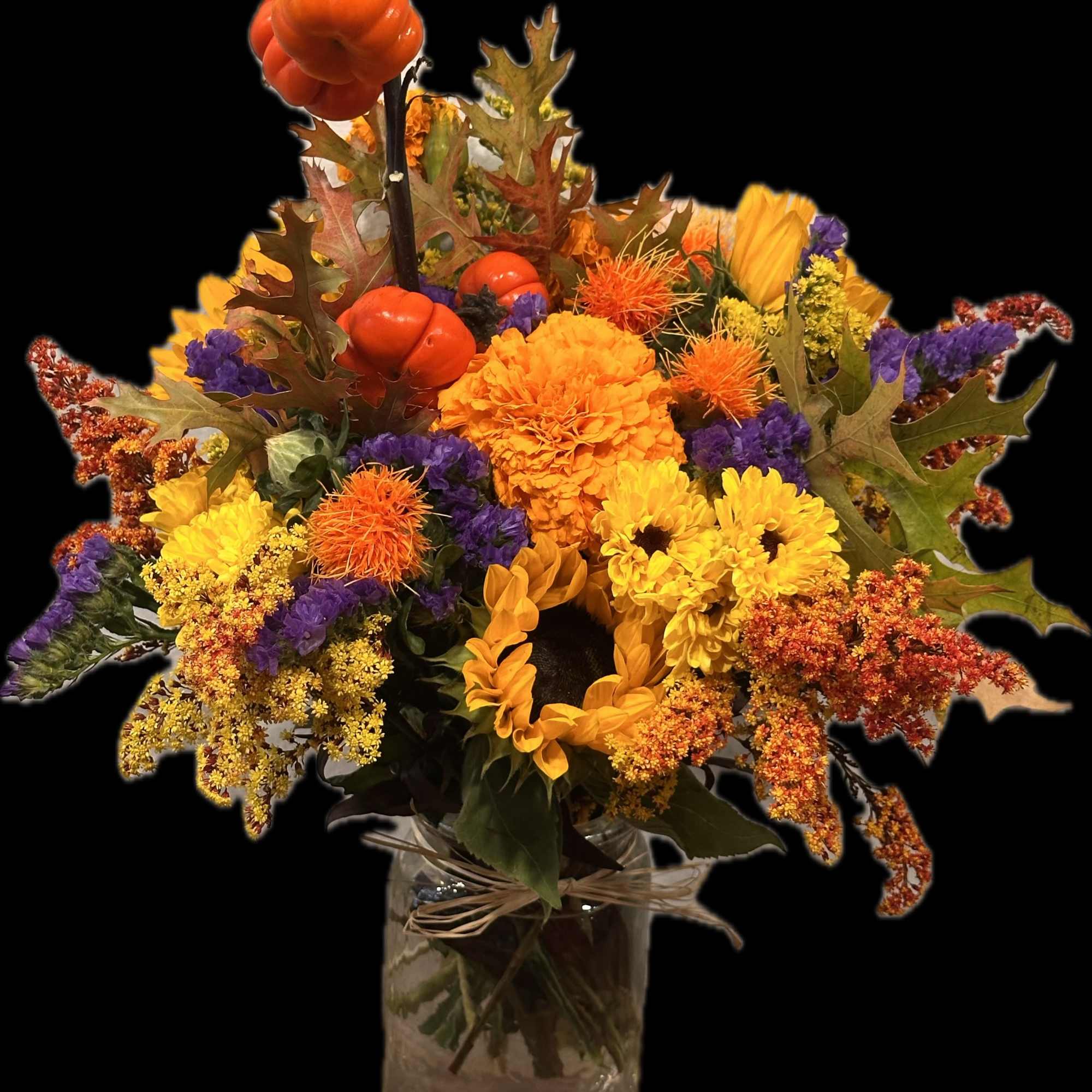 Autumn bouquet of sunflowers, chrysanthemums, and orange pumpkins in a glass vase