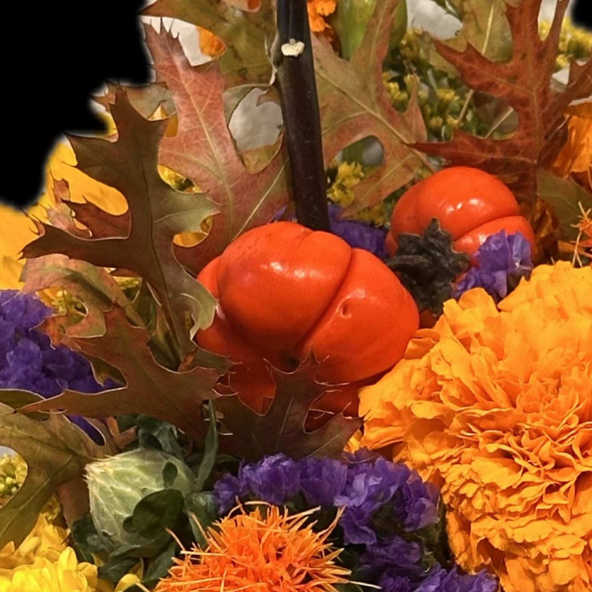 Autumn floral arrangement with orange pumpkins and yellow, purple, and orange flowers