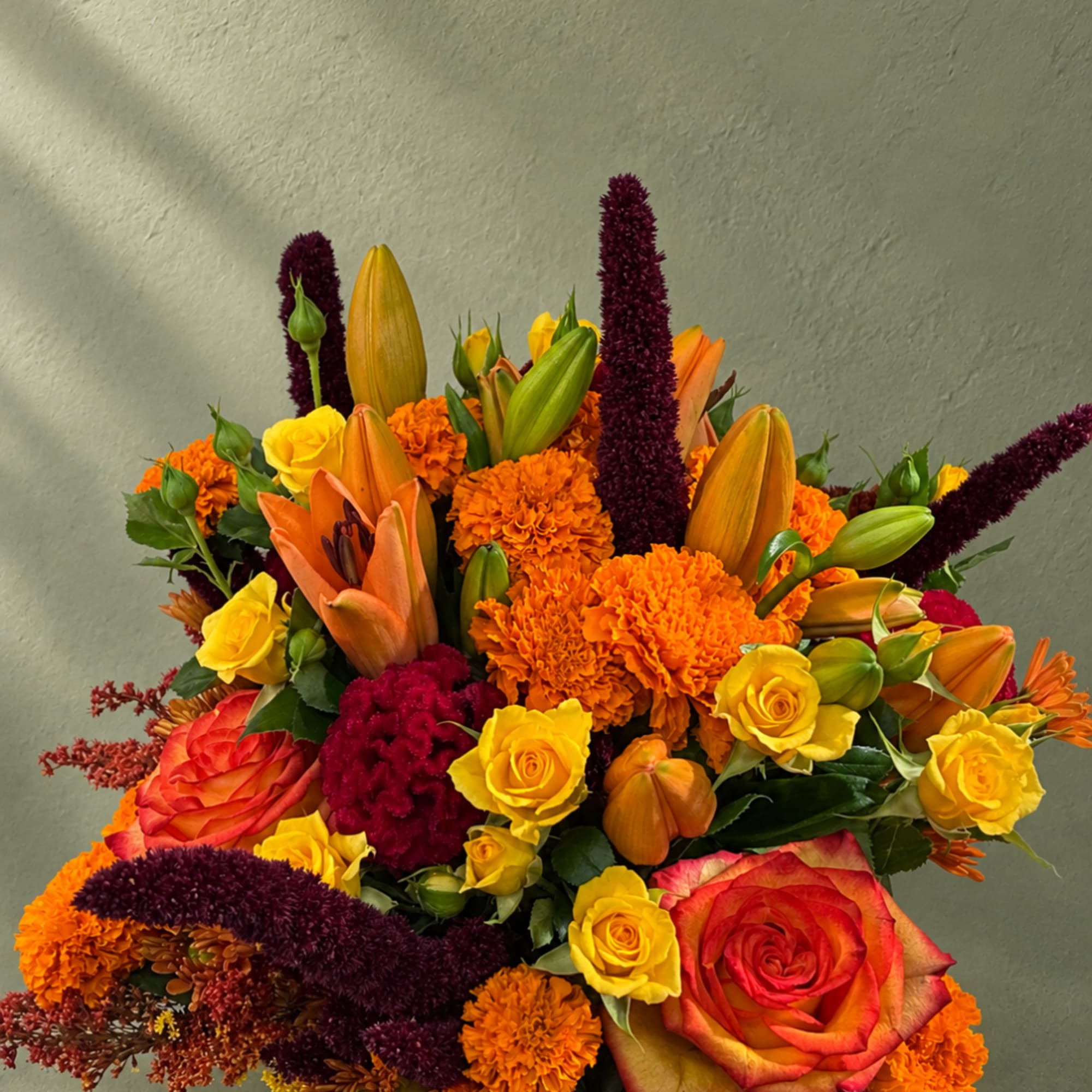 Bright mixed bouquet with roses, lilies, and marigolds in orange, yellow, and burgundy