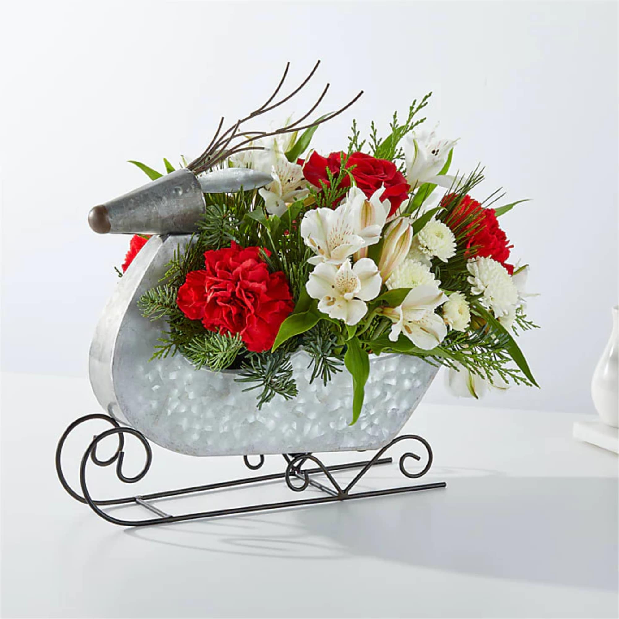 Red and white floral arrangement in a metal sleigh container