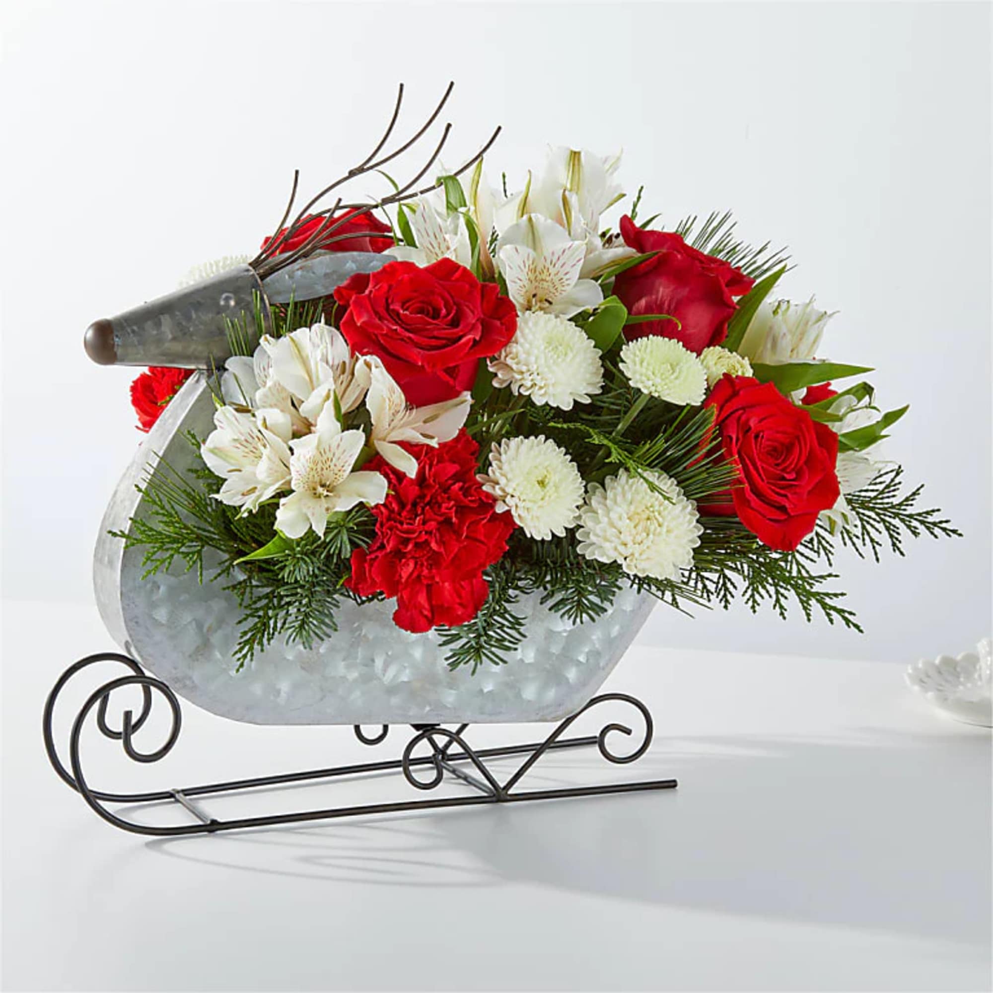 Red roses and white flowers arranged in a sleigh-shaped metal container