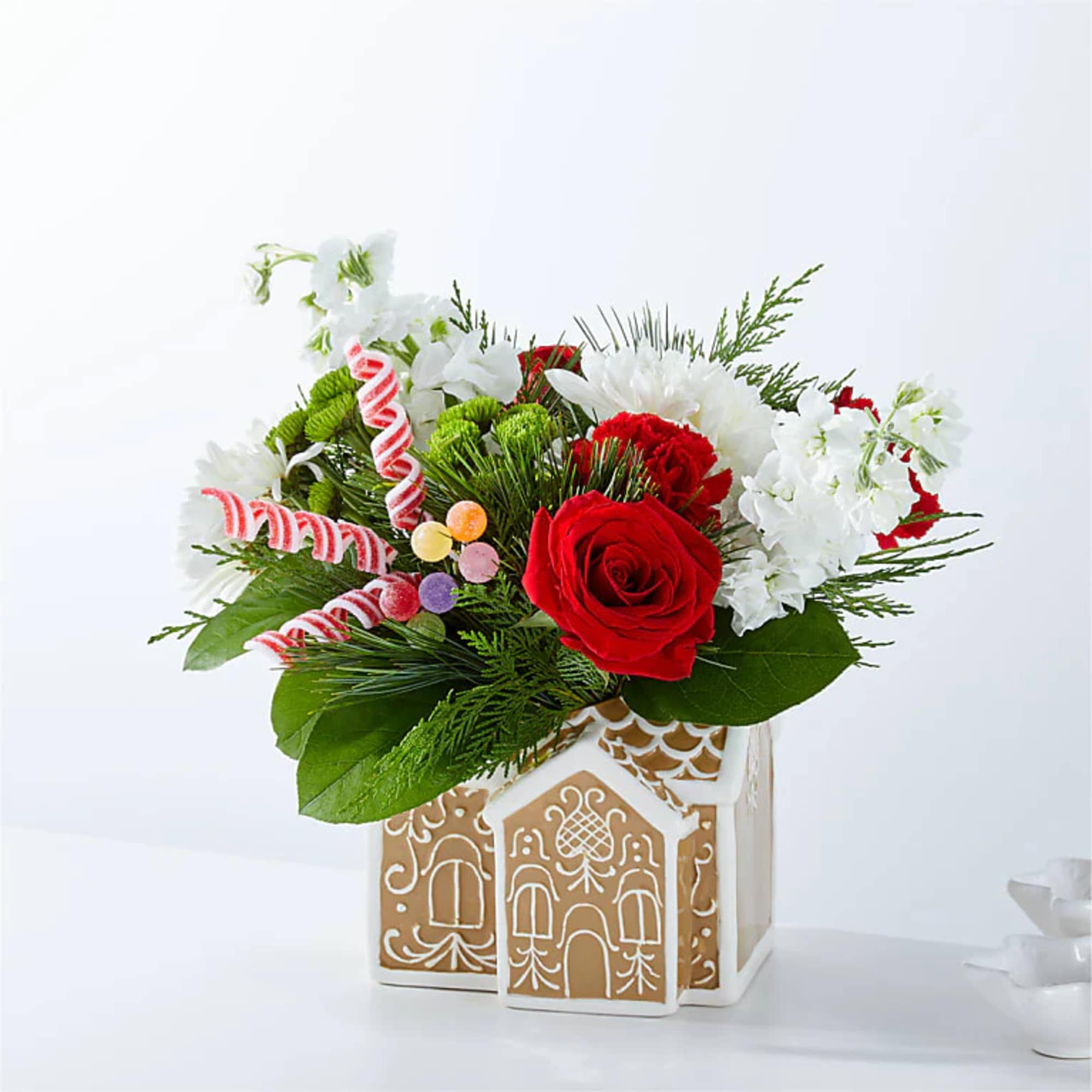 Red roses and white flowers in a decorative house-shaped container