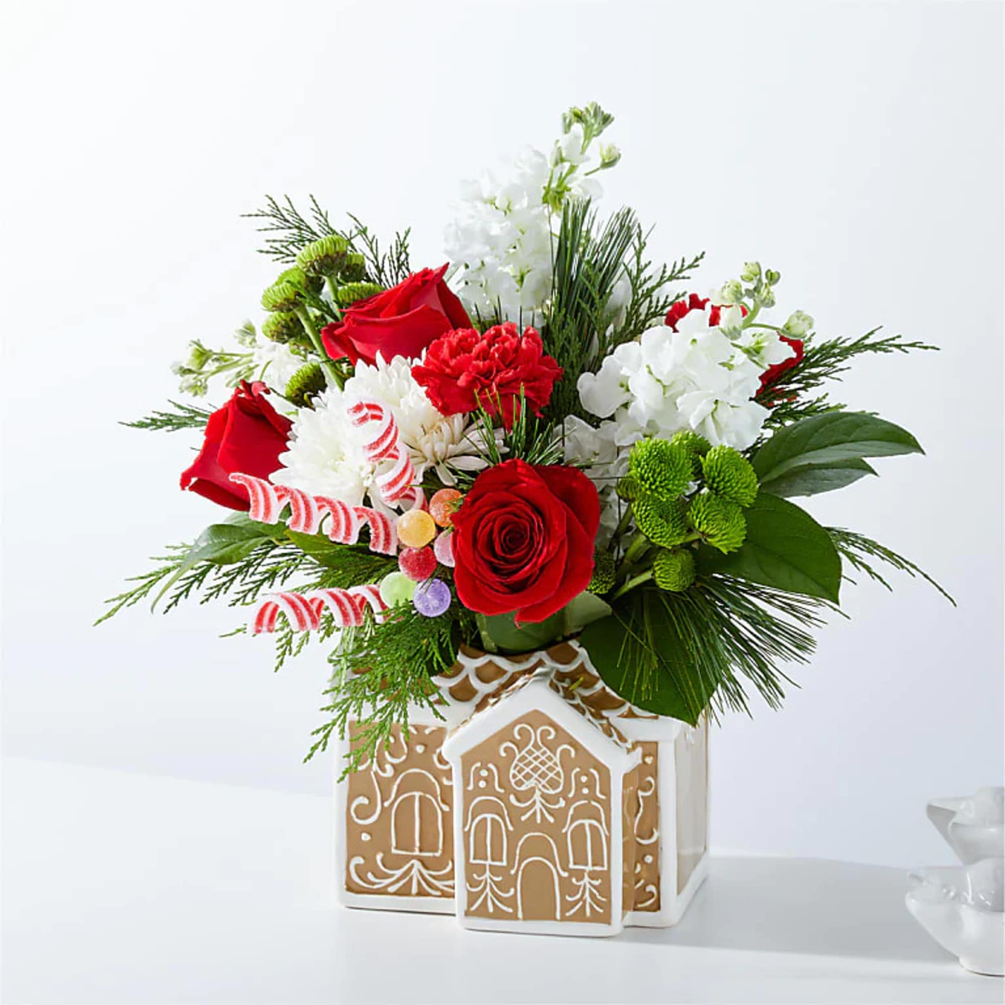 Red roses and white flowers in a gingerbread house vase