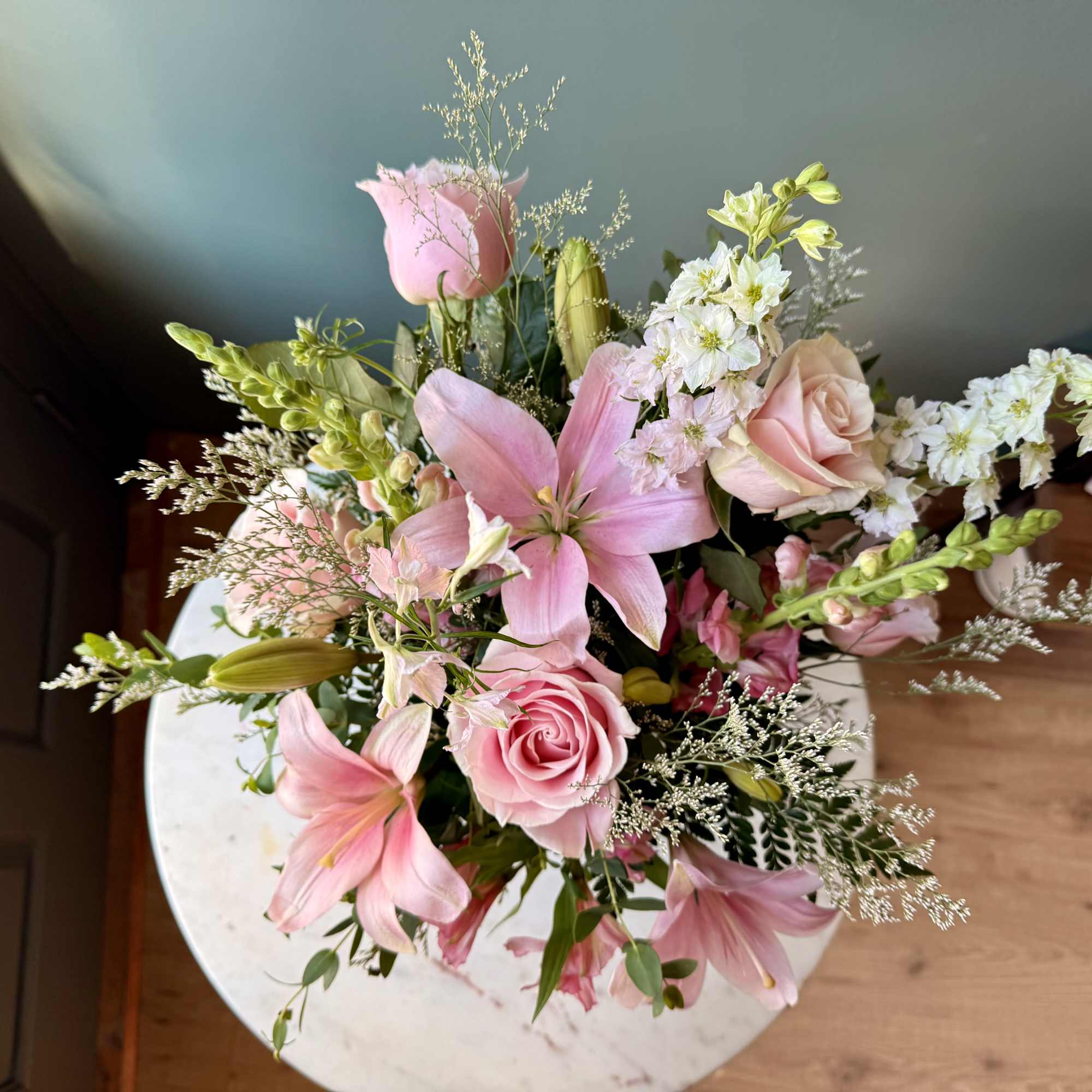 A soft, romantic floral arrangement featuring beautiful blooms in layered shades of