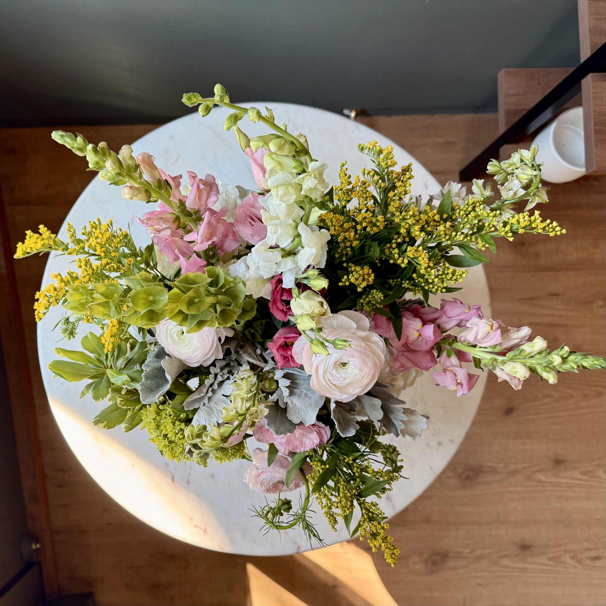 Pink and white mixed bouquet with yellow filler flowers on a round table