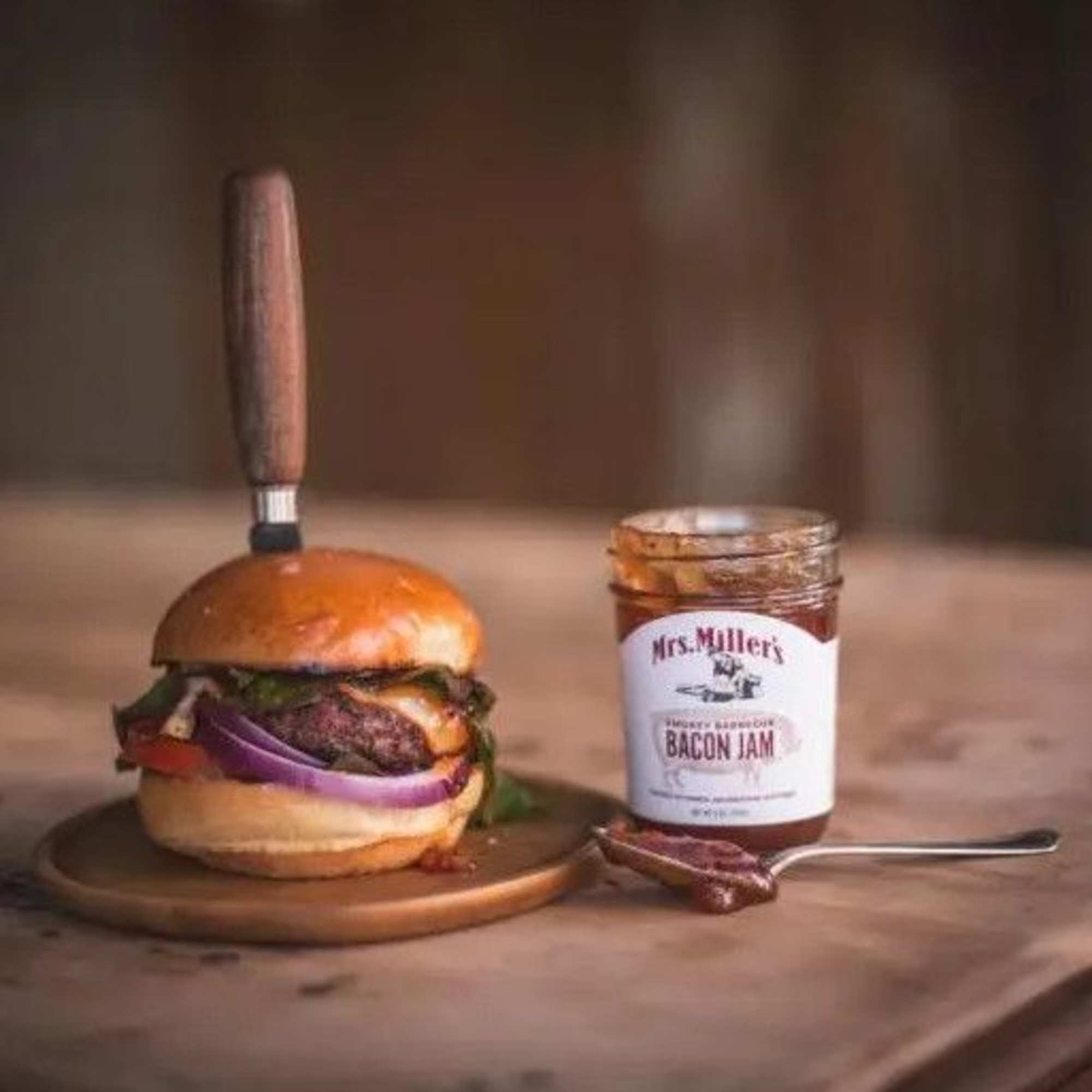 Burger on a plate beside a jar of bacon jam