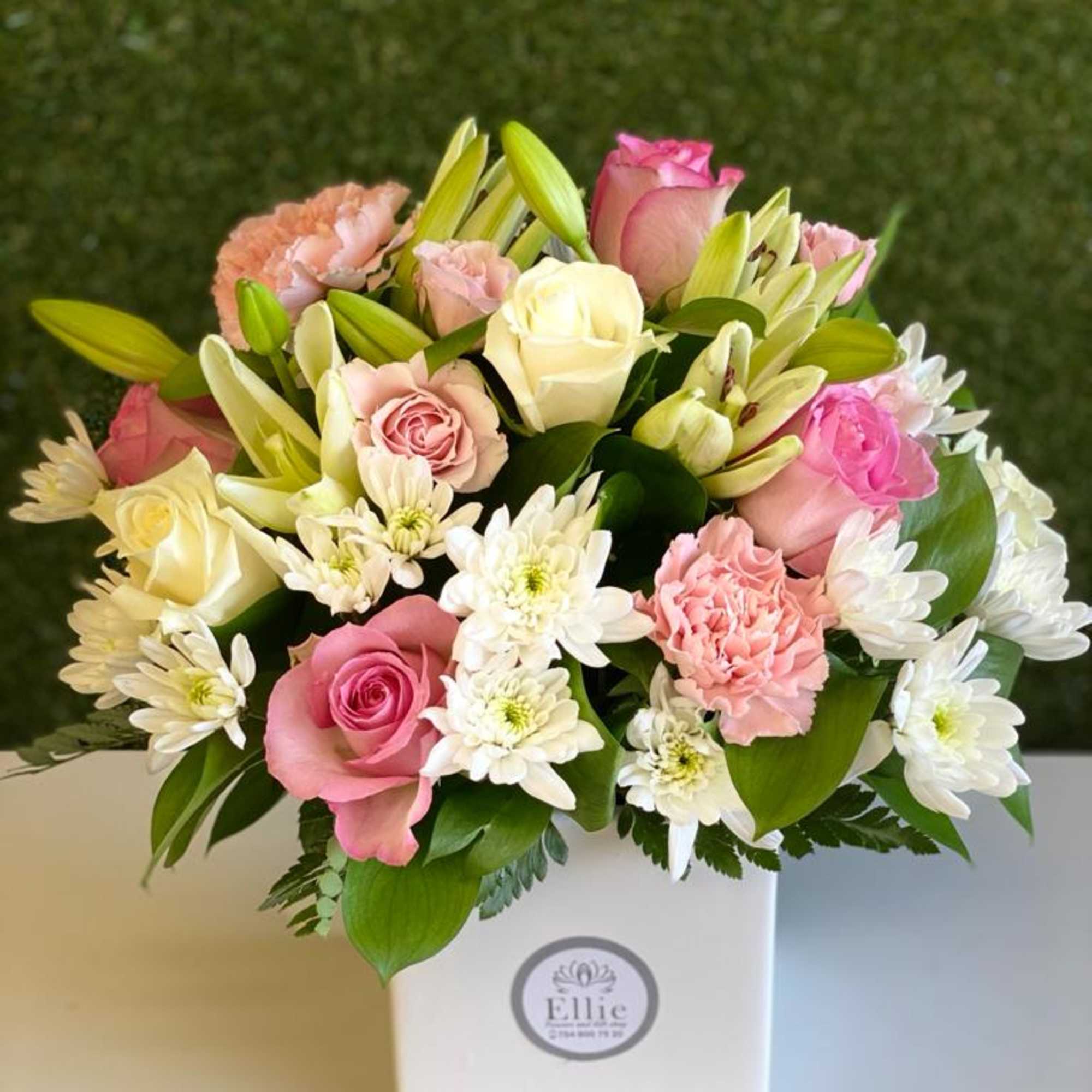 Pink and white bouquet with roses, lilies, carnations, and daisies in a white box