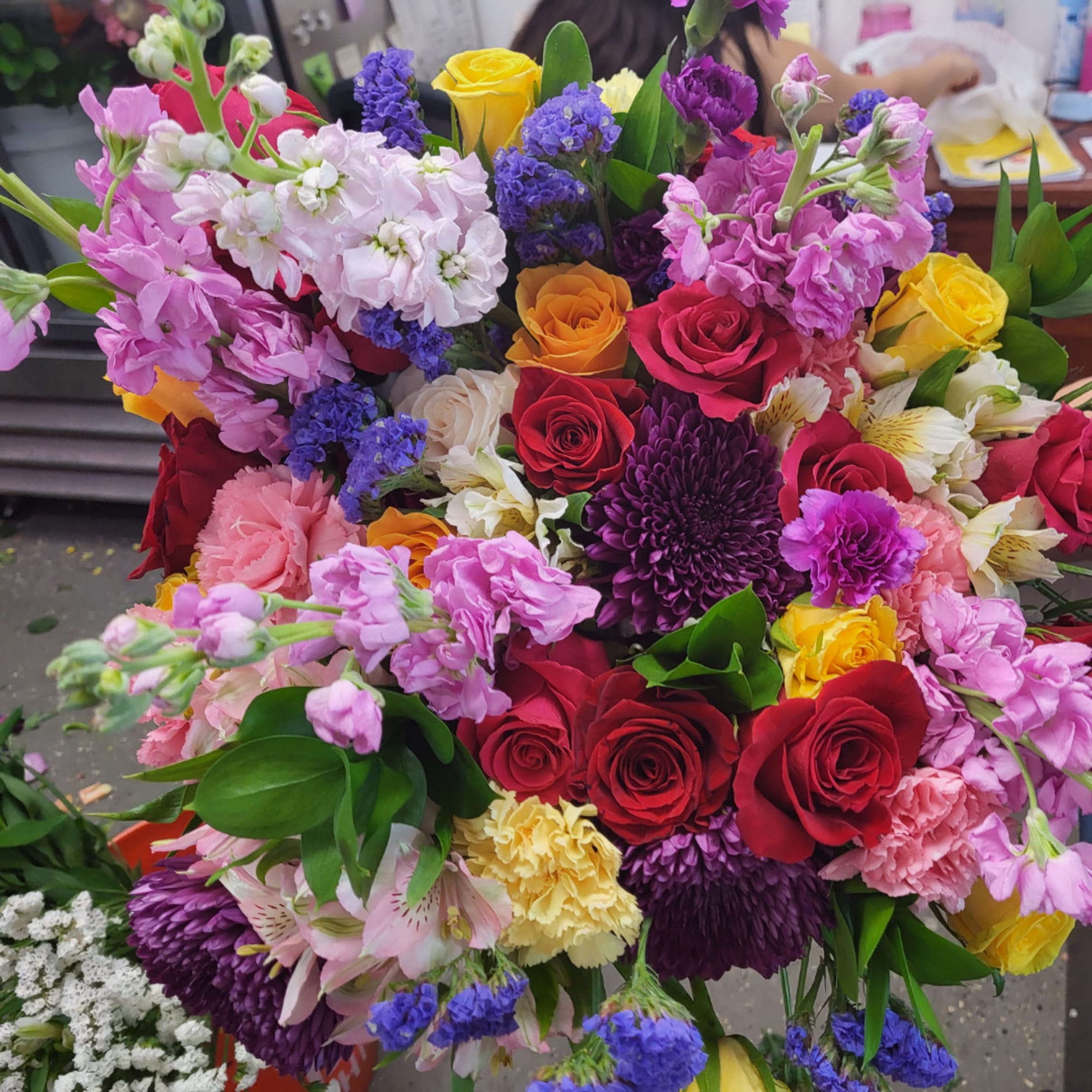 Mixed bouquet of roses, carnations, and purple blooms in bright colors