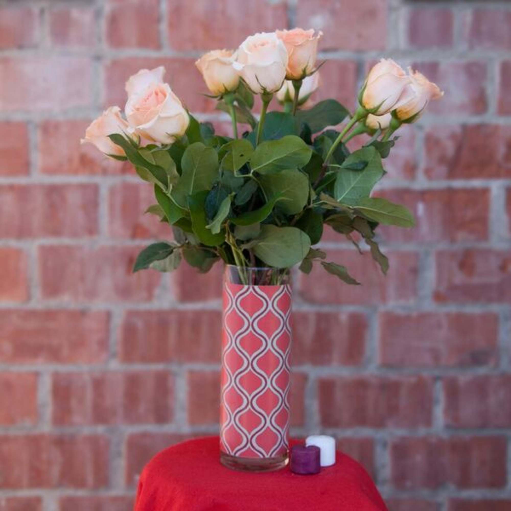 Peach roses in a patterned glass vase with two small candles, photo 2 of 3