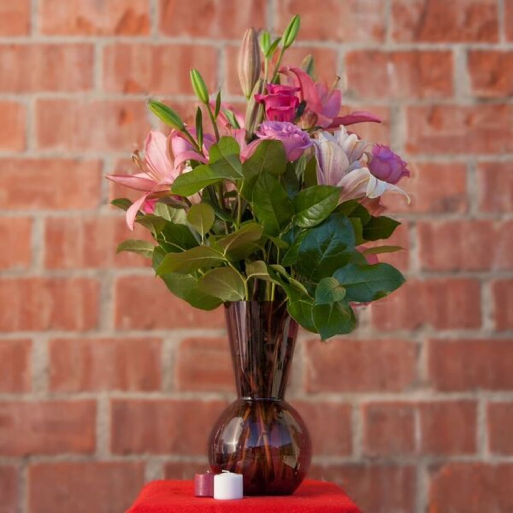 Pink and purple flowers in a tall brown glass vase