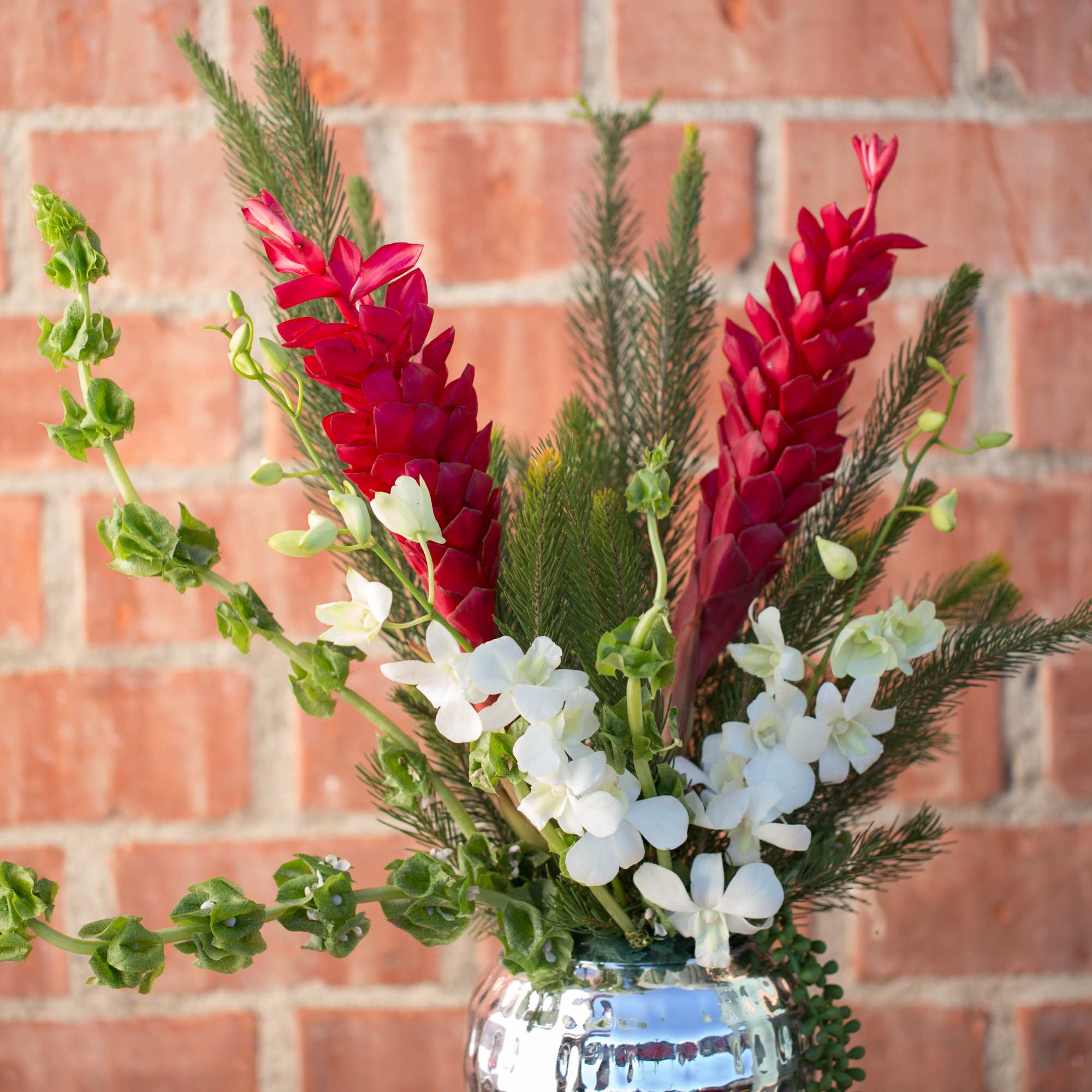 Red and white tropical flowers in a silver vase