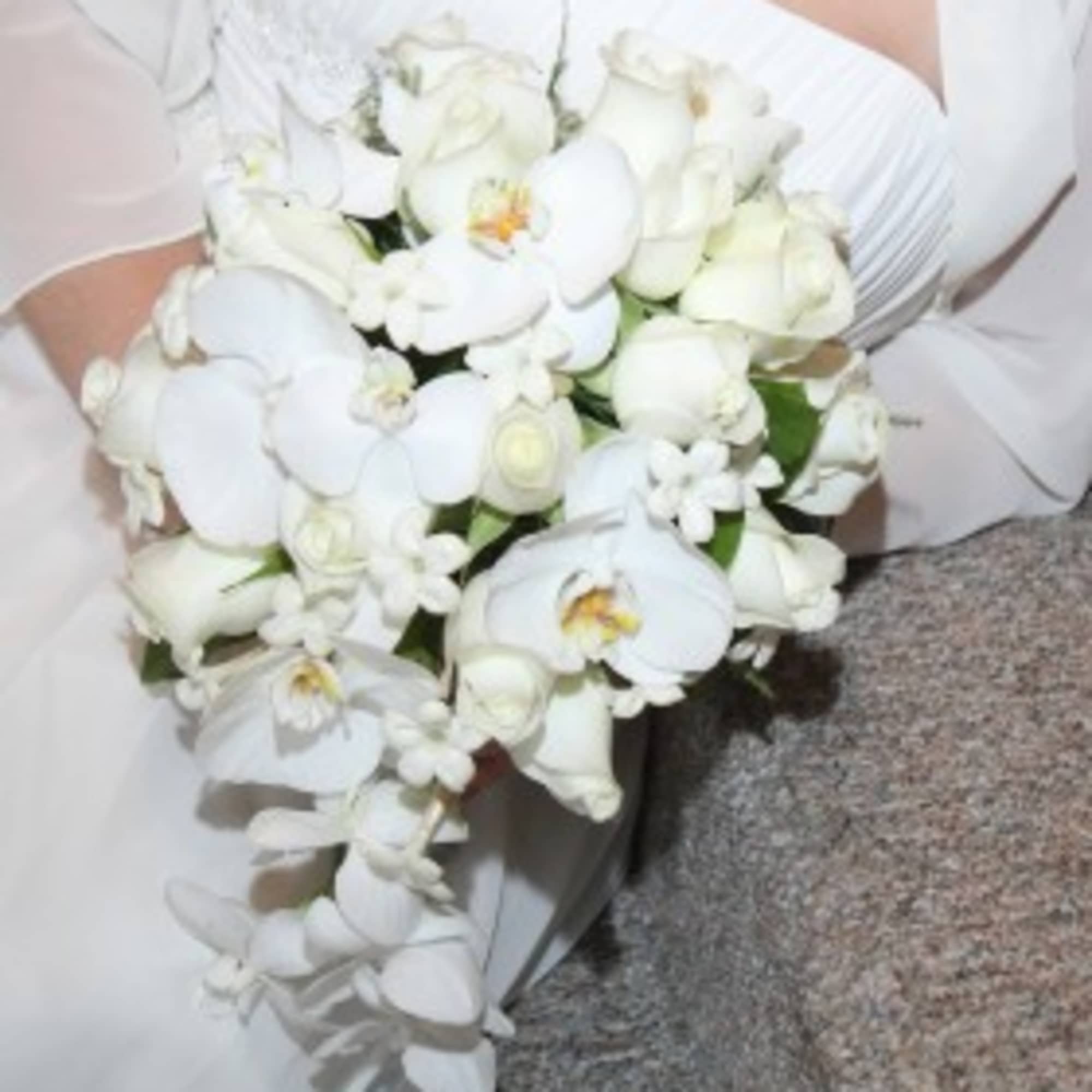White orchid and rose bouquet held by a person in white