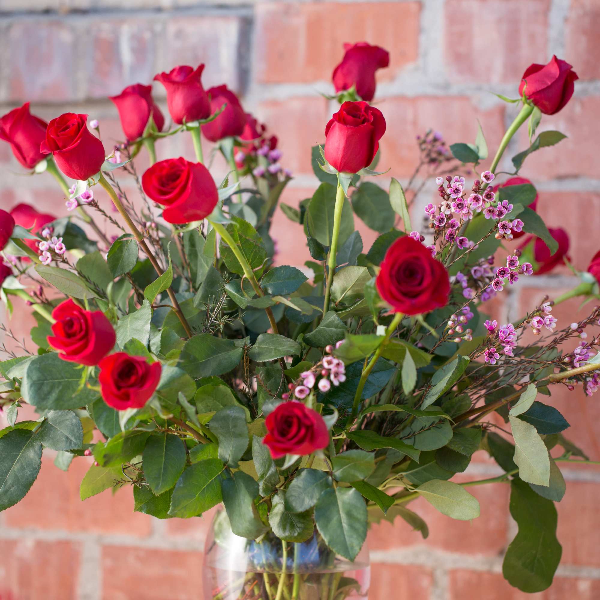 Bouquet of red roses with small pink filler flowers in a glass vase