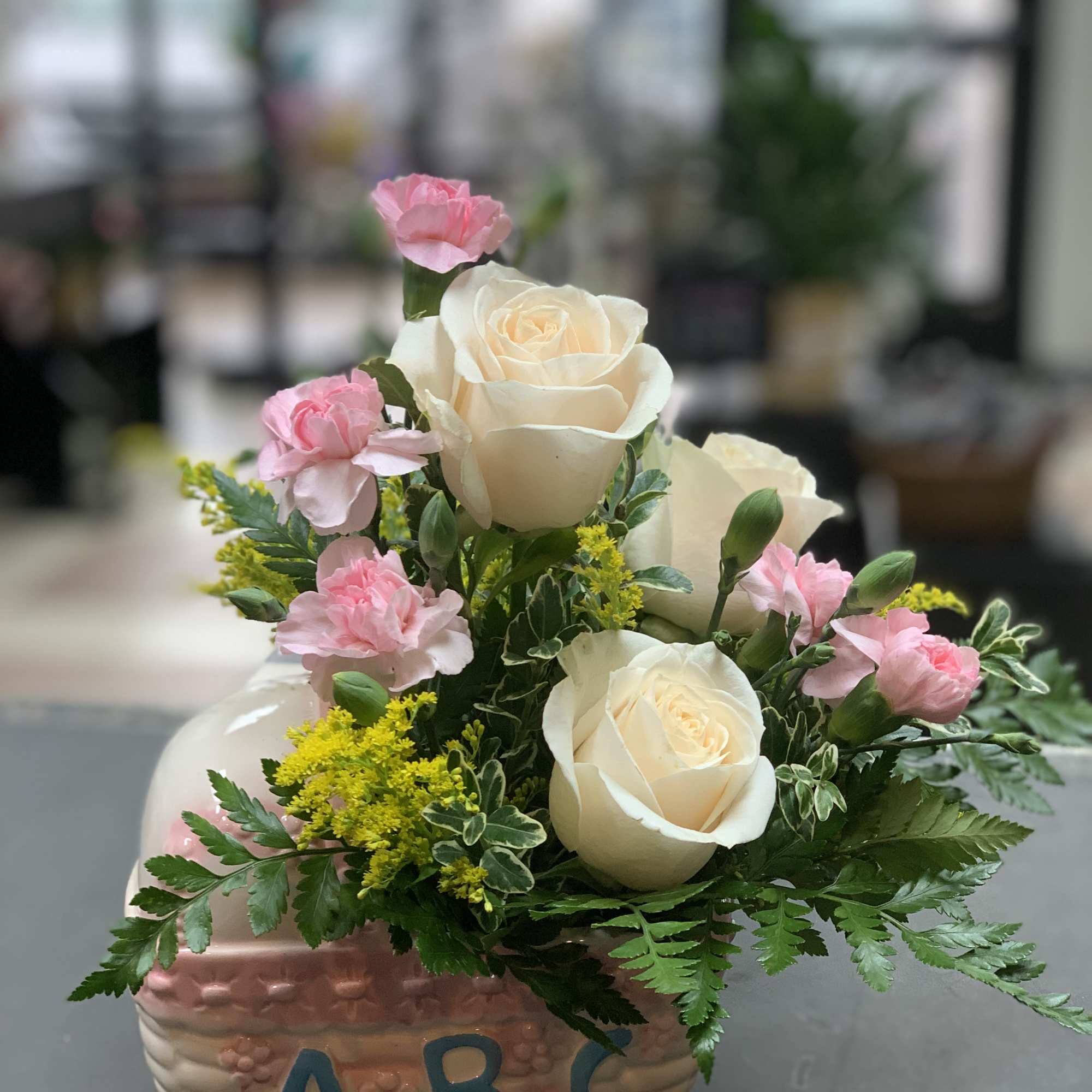 Pink carnations and white roses in a decorative ceramic container