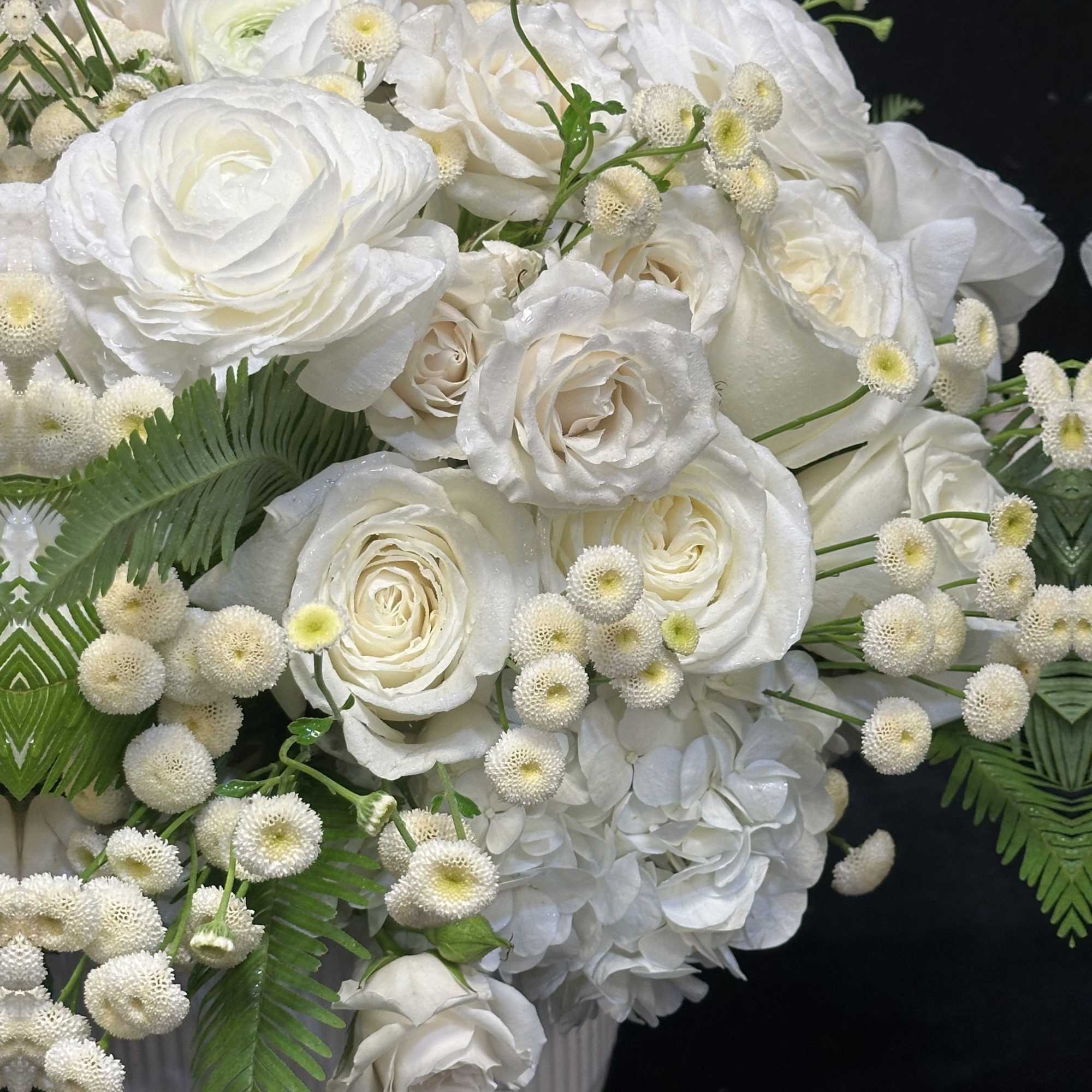 White roses and hydrangeas in a white vase with small white filler flowers