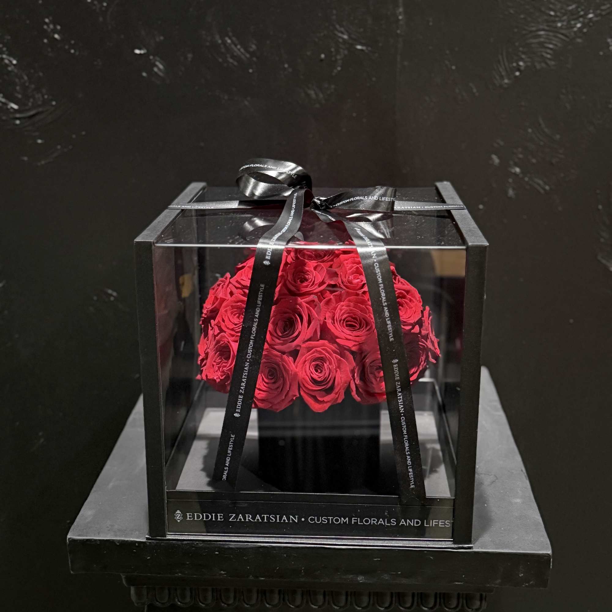 Red roses in a clear square box tied with a black ribbon