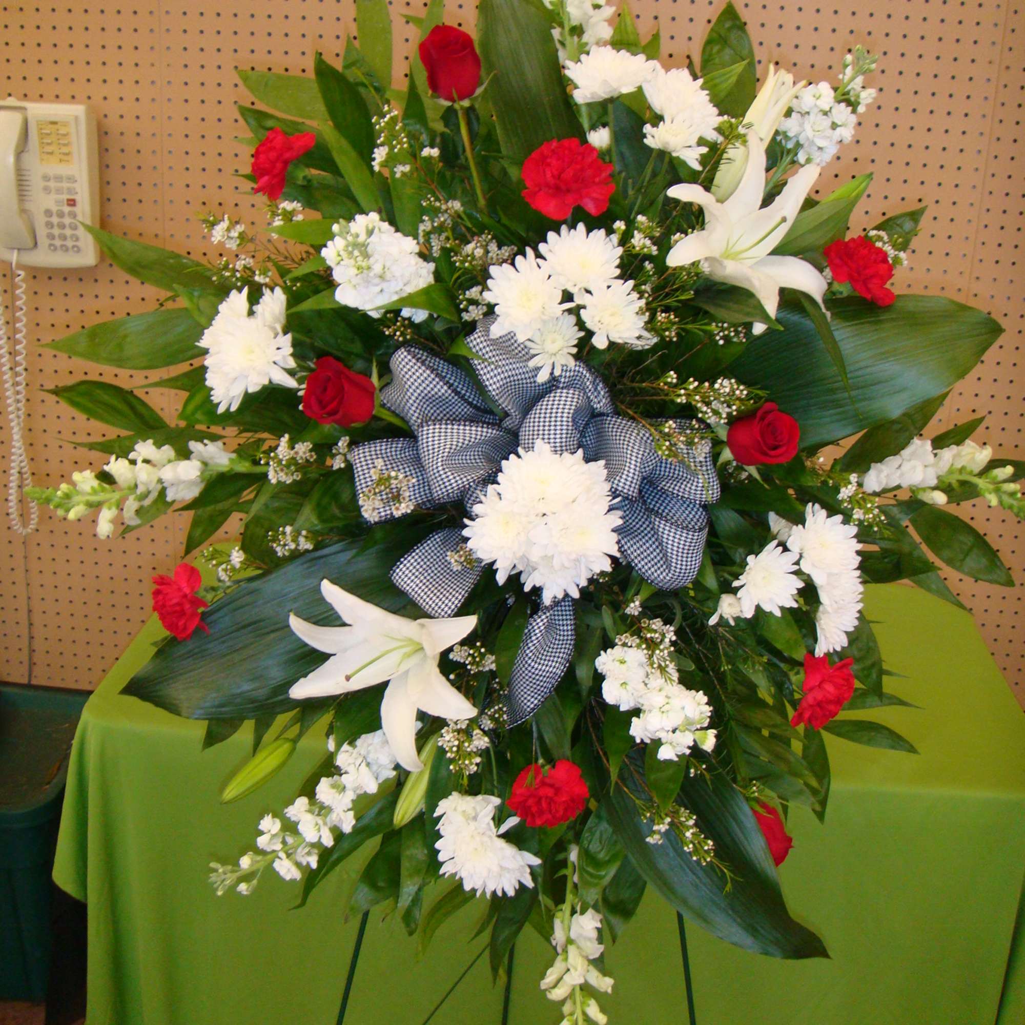 Standing floral spray with red and white flowers and a plaid bow
