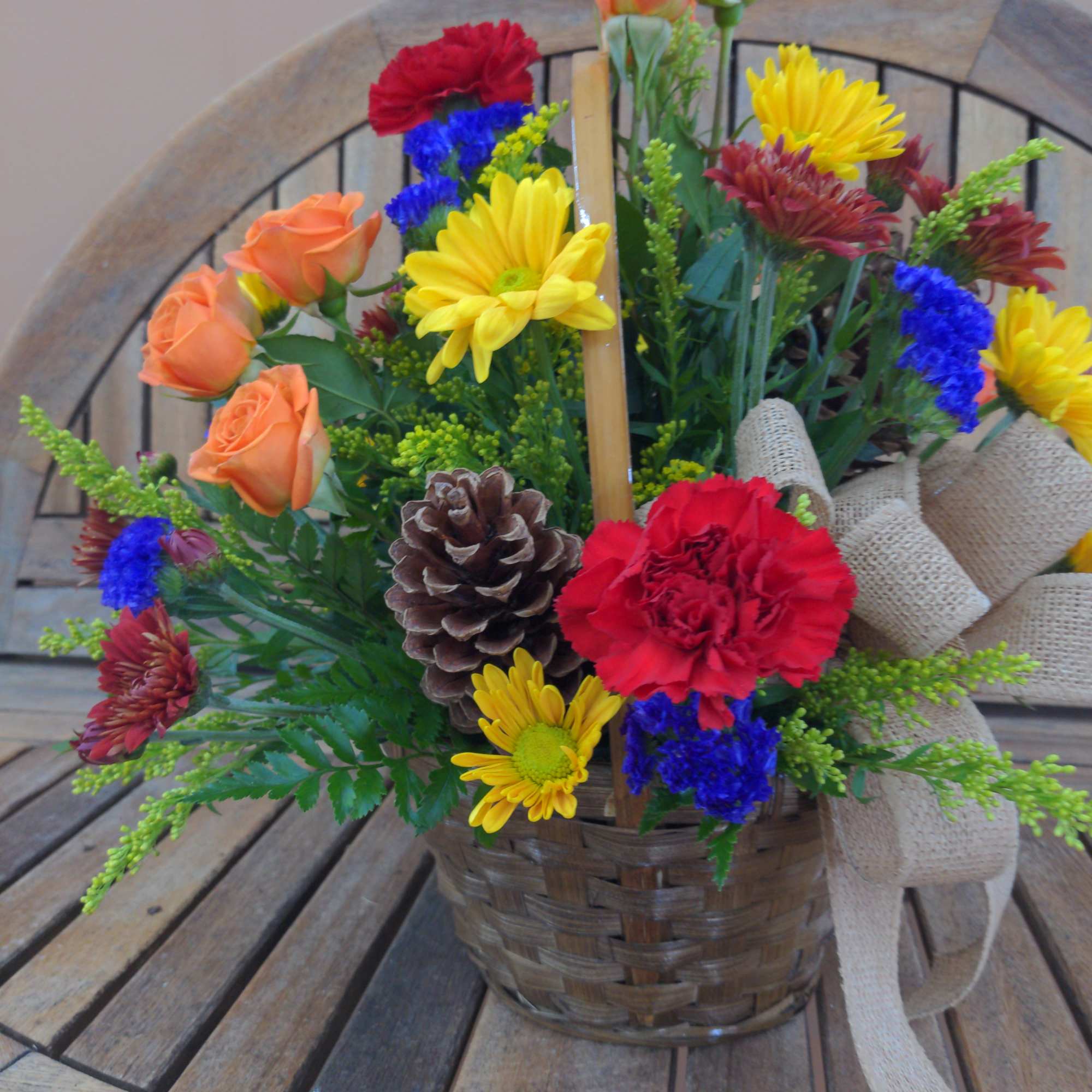 Basket arrangement with orange roses, daisies, and a burlap bow