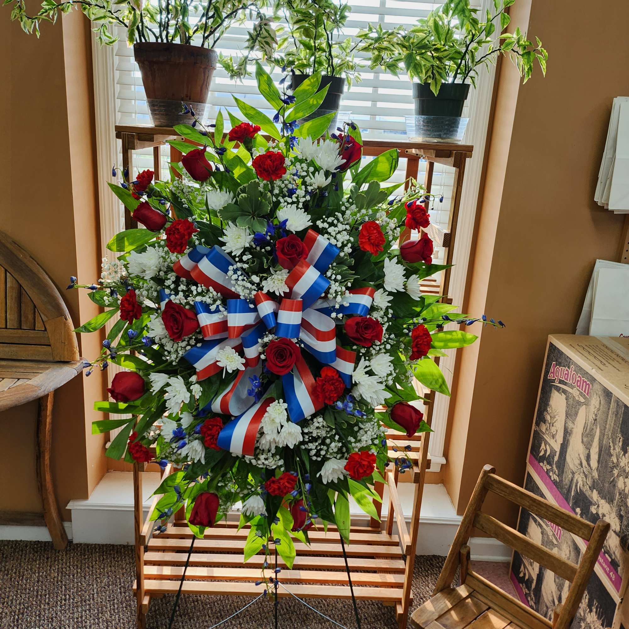 Standing floral wreath with red, white, and blue flowers and ribbon