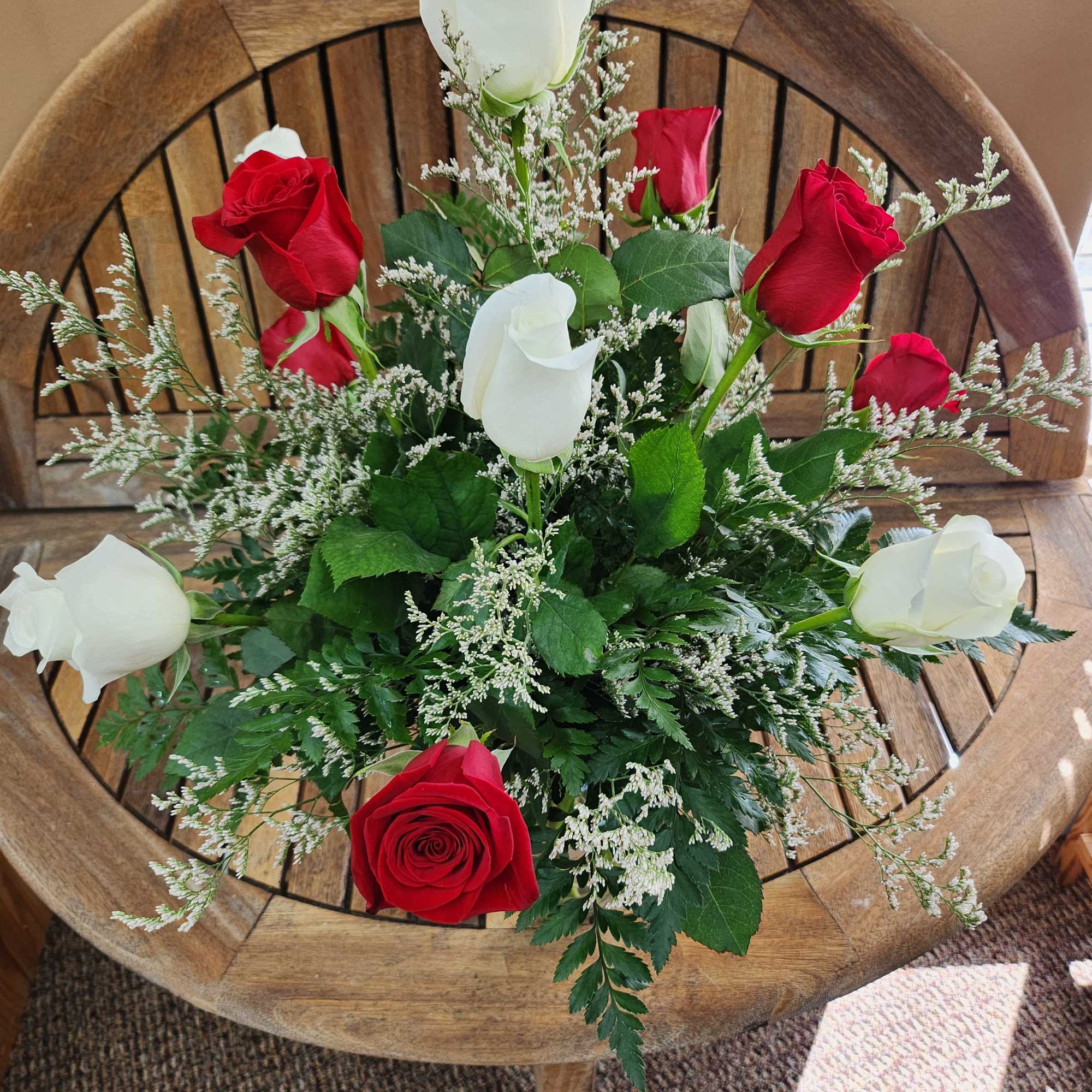 Red and white roses arranged with airy filler on a wooden chair