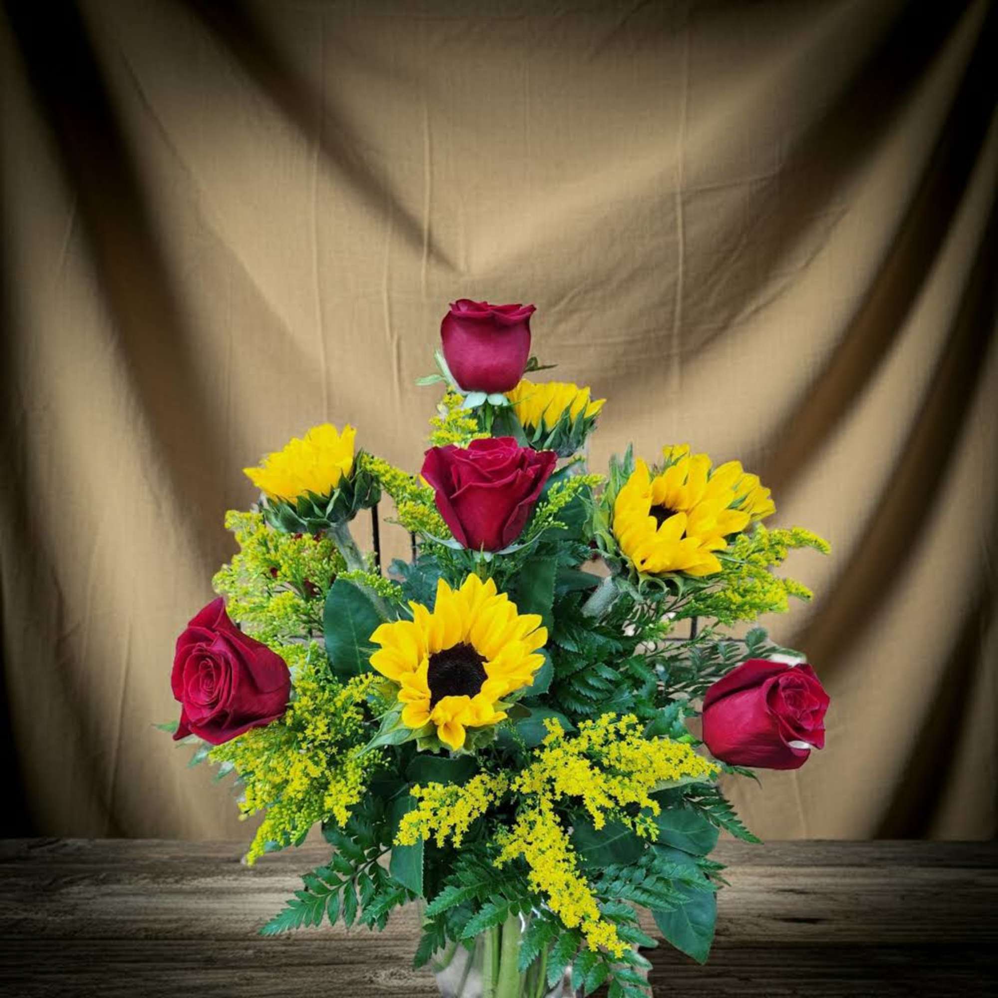 Bouquet of red roses and yellow sunflowers in a glass vase