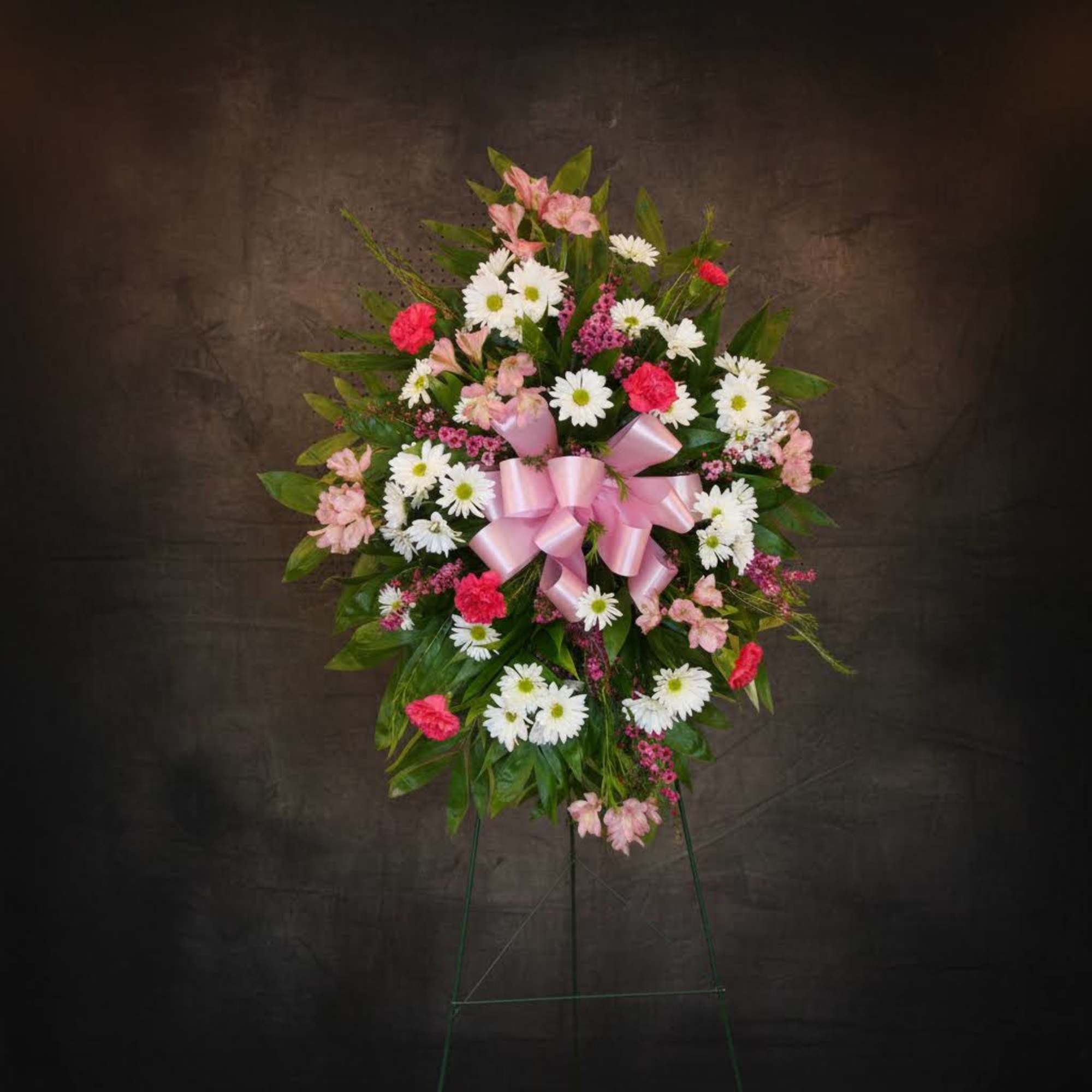 Standing floral spray with pink and white flowers and a pink ribbon bow