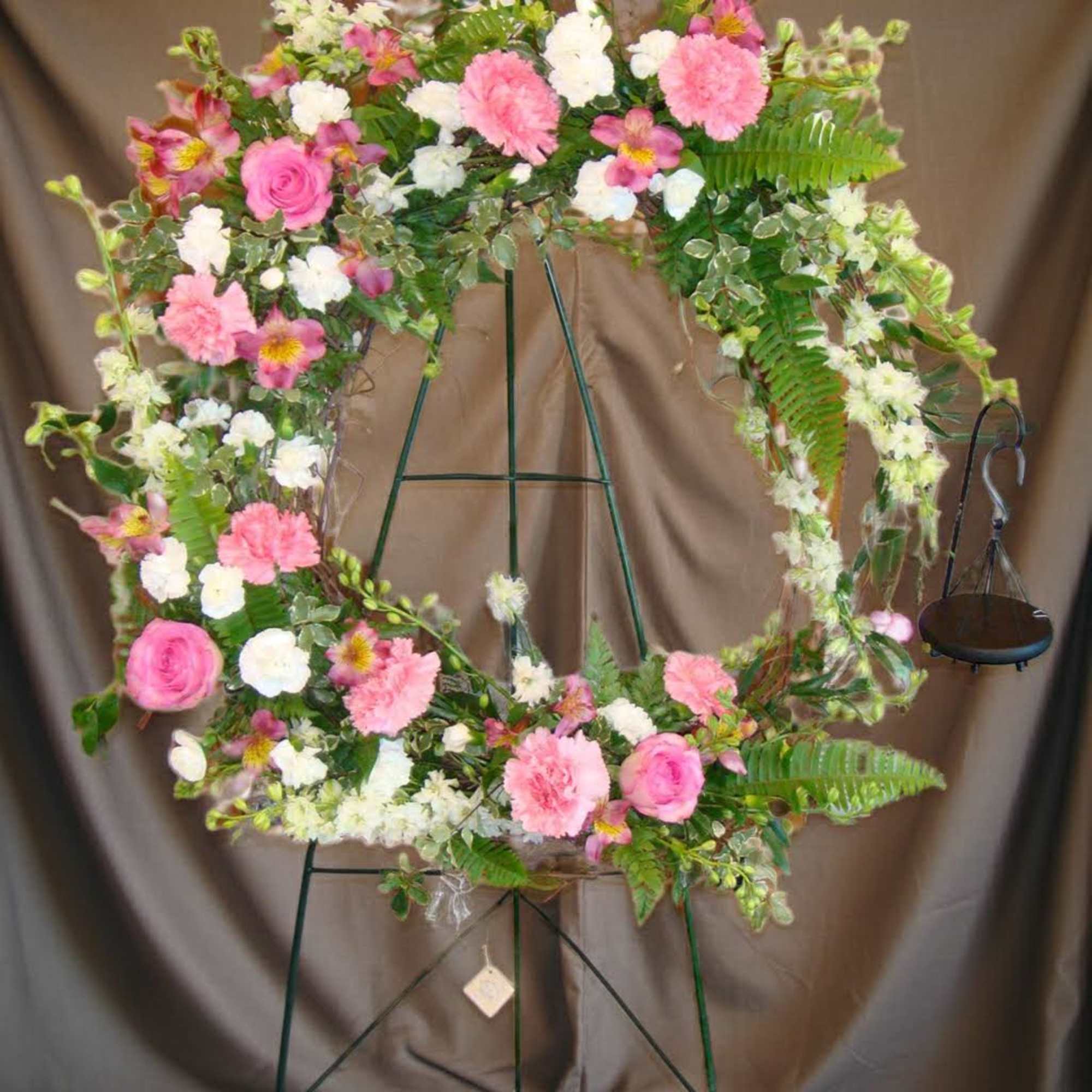 Floral wreath with pink and white flowers on a metal stand