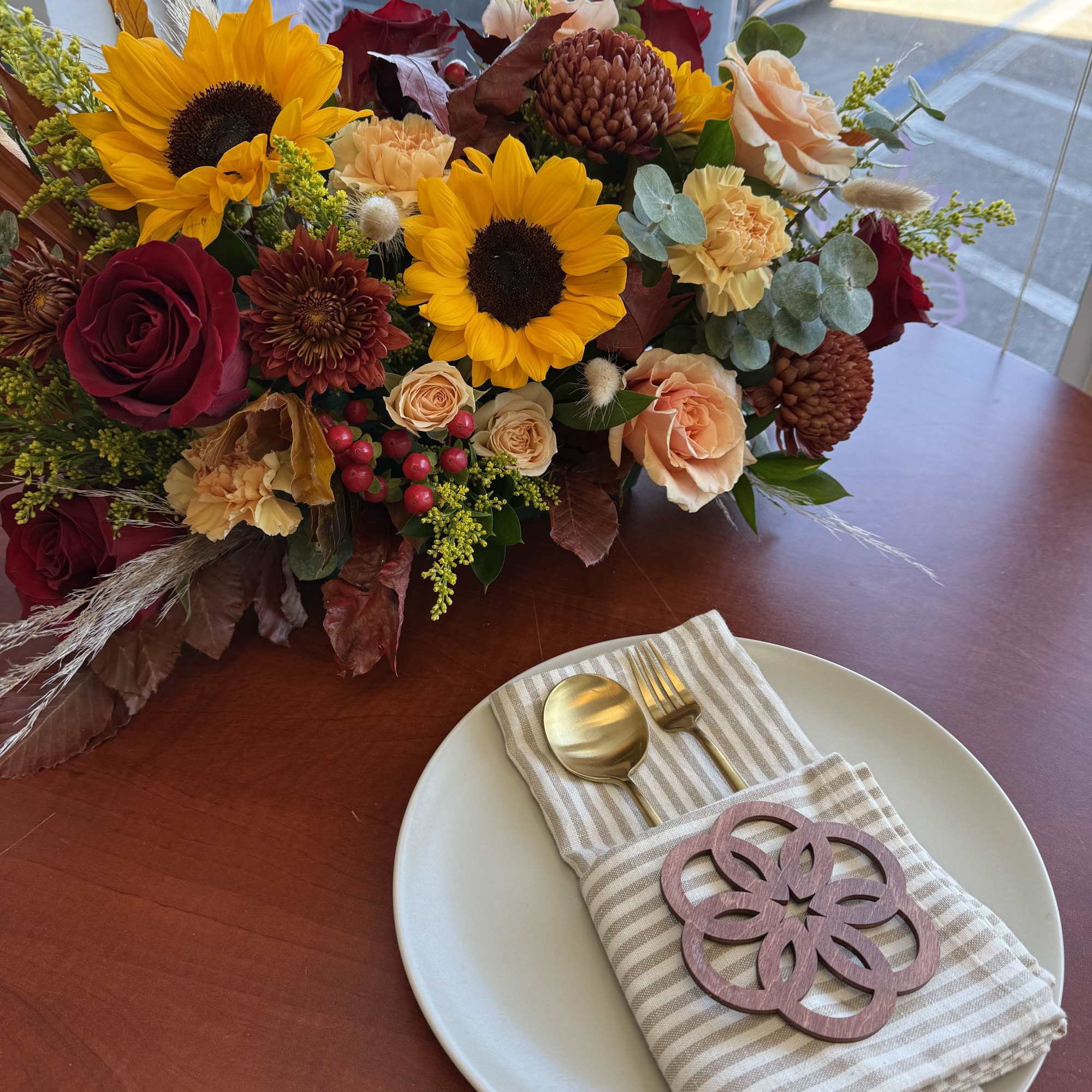 Mixed bouquet with sunflowers, roses, and mums on a table setting