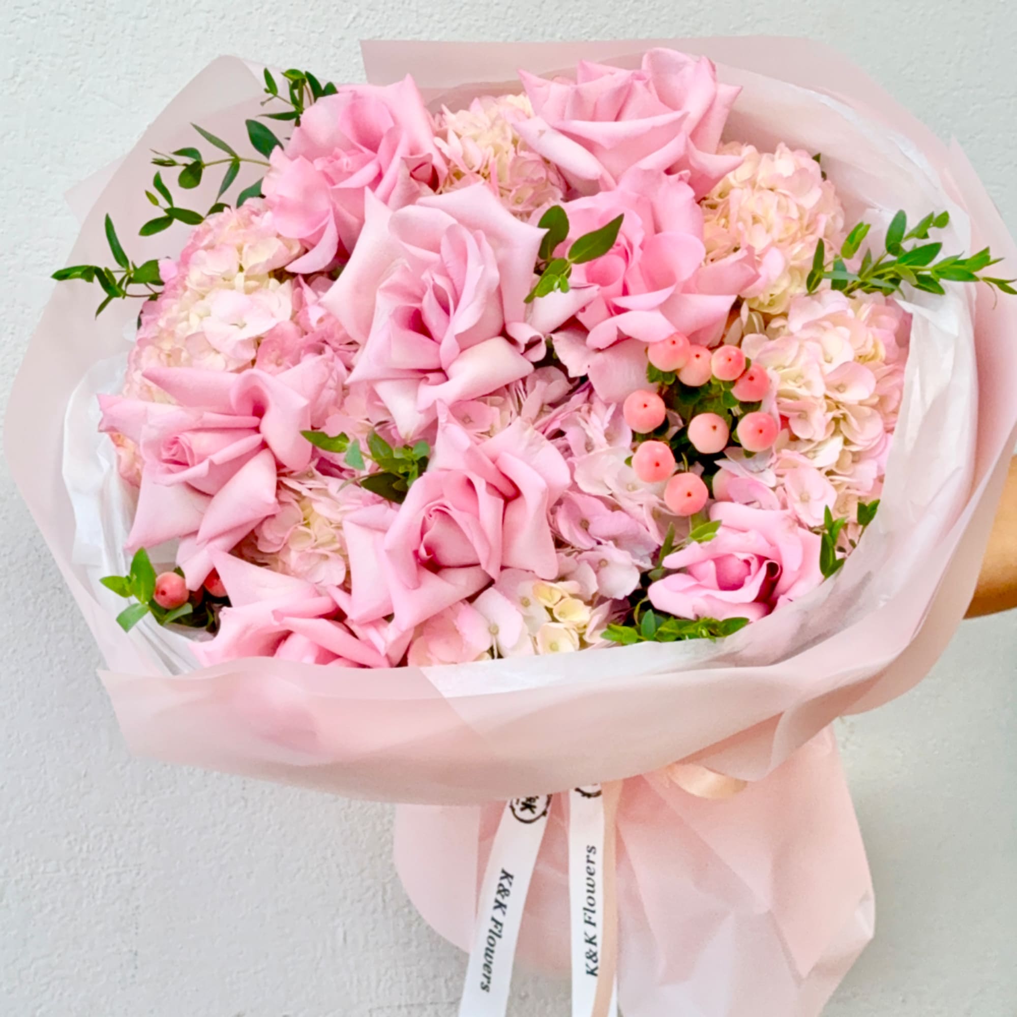 Pink rose bouquet with pale hydrangeas and berry accents wrapped in blush paper, photo 2 of 4