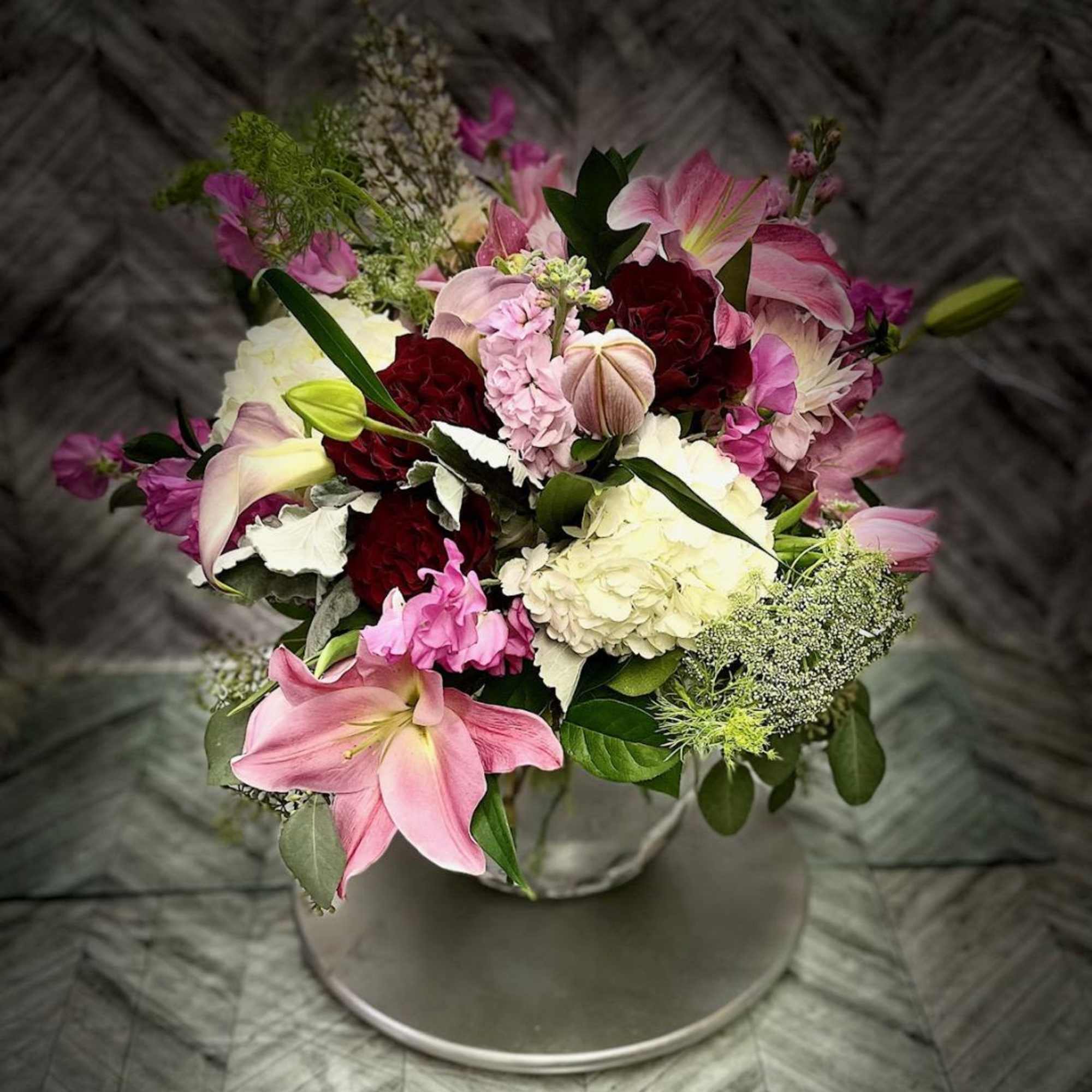 Pink and white mixed flower bouquet in a round container