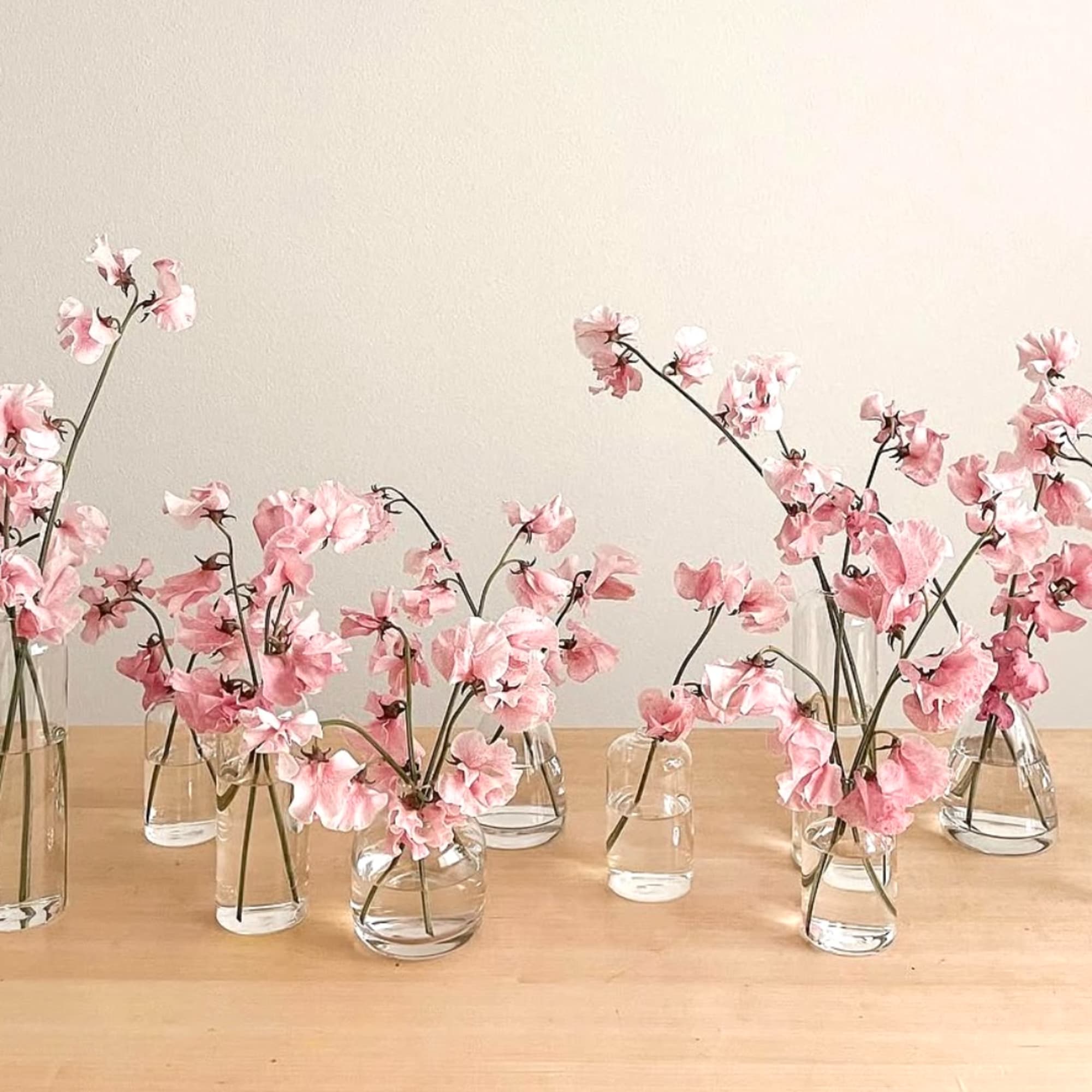 Pink flowers in small glass vases on a wooden table