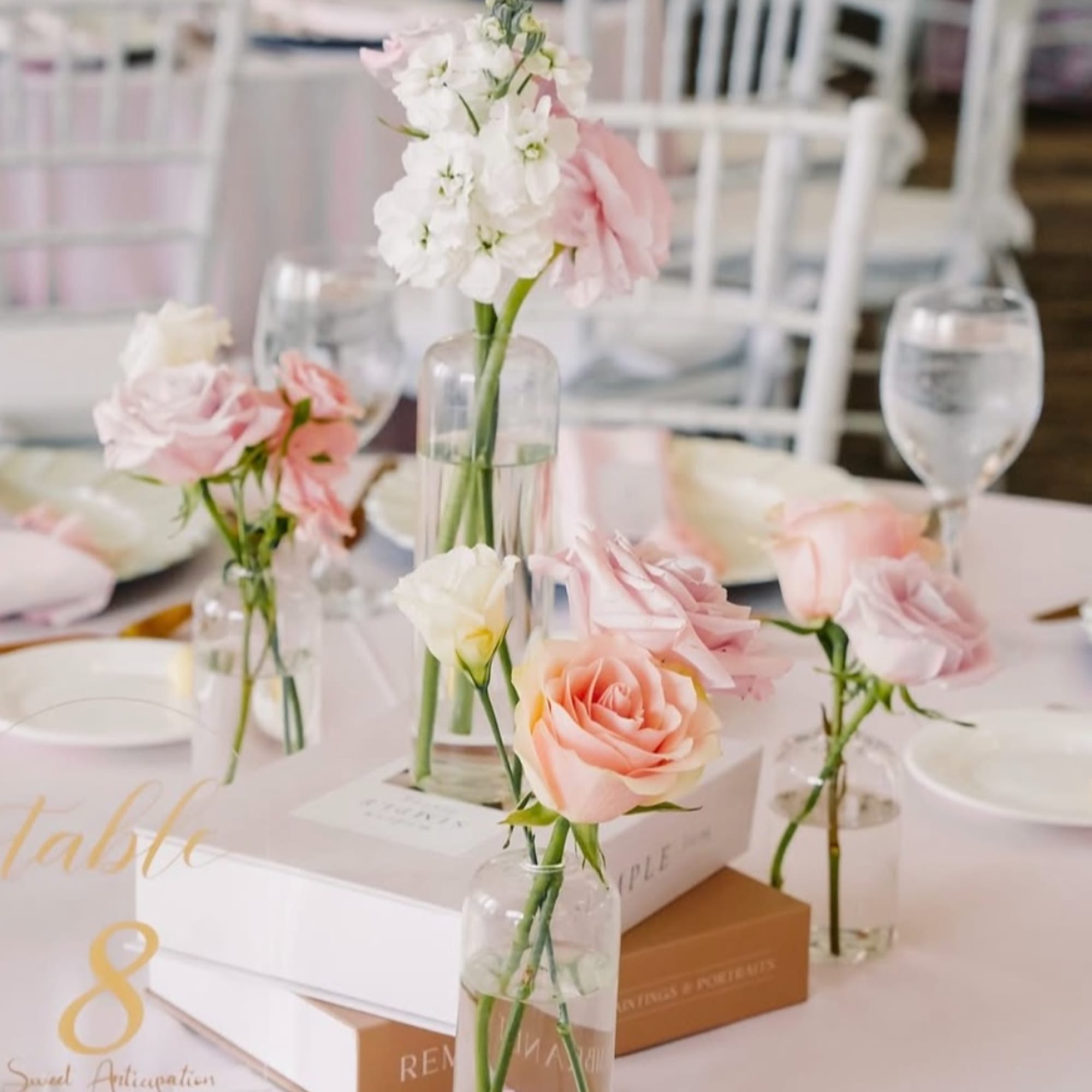 Pastel pink and white flowers in small glass vases on a table centerpiece