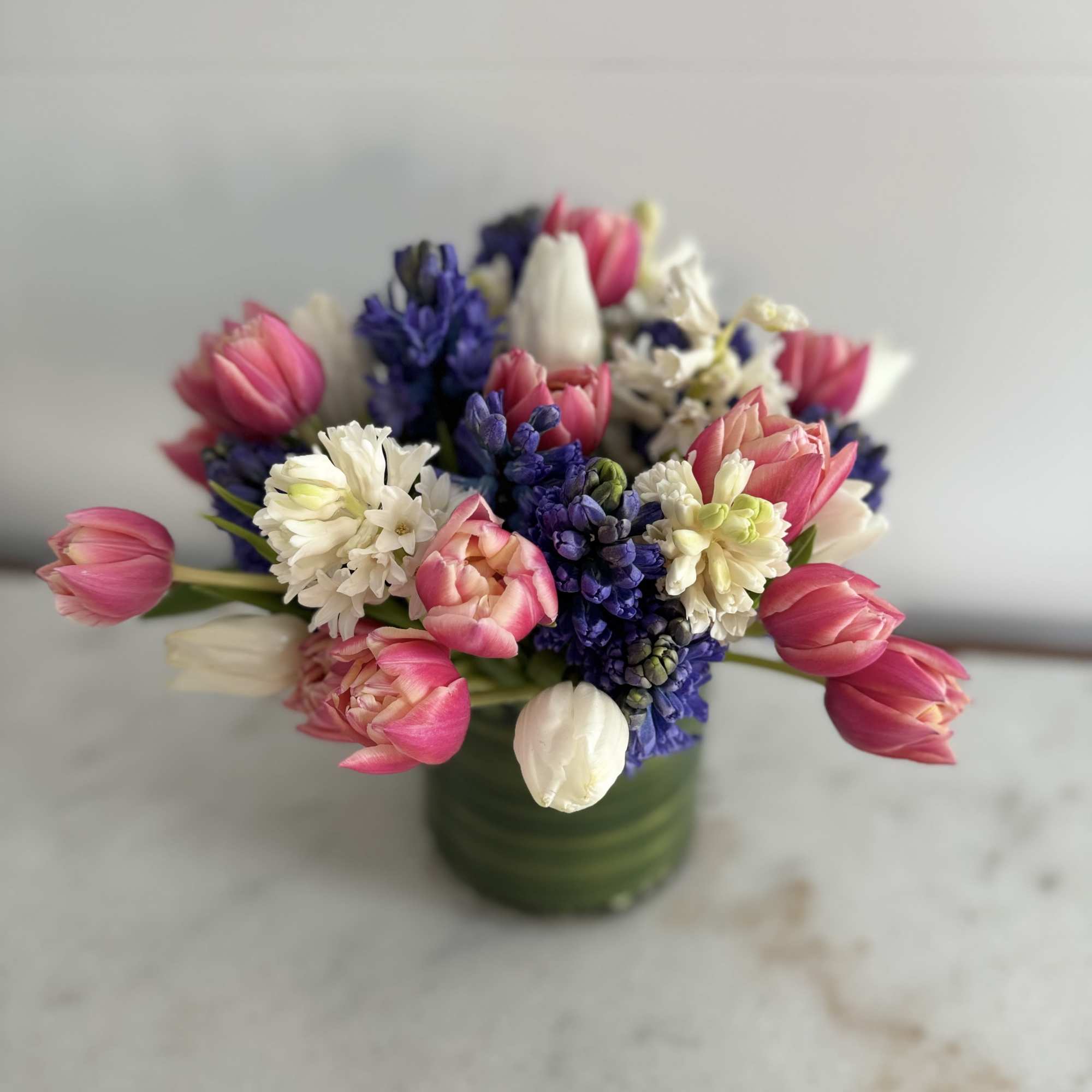 Pink and white tulips with purple and white hyacinths in a green vase