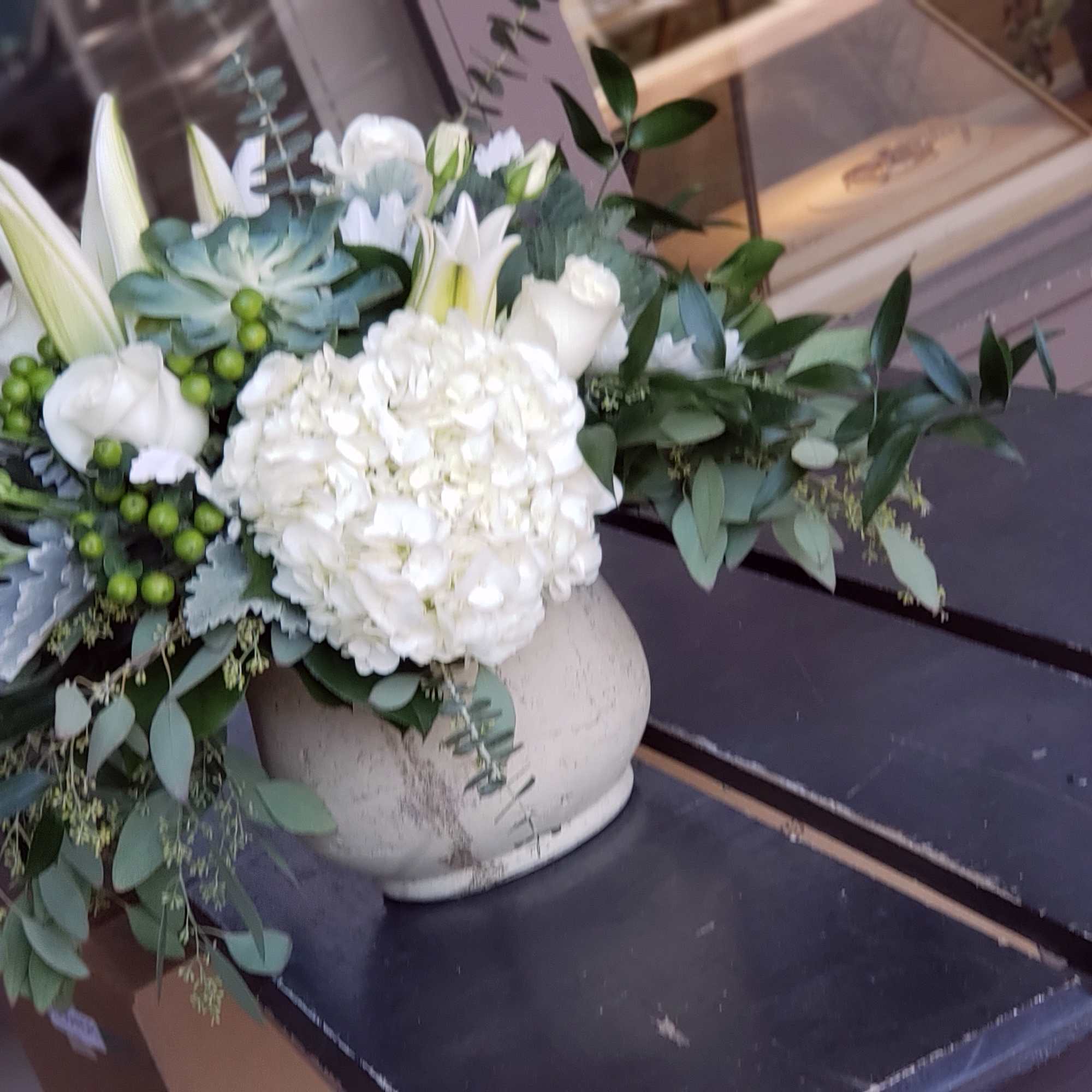 White floral arrangement in a ceramic vase with lilies and hydrangea