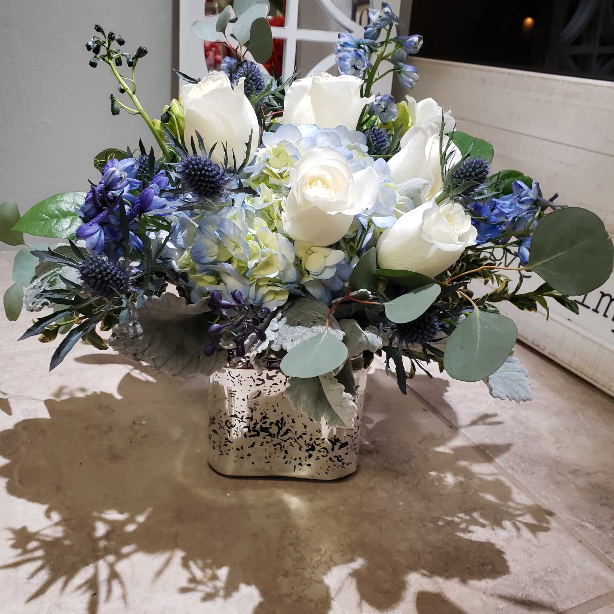 White and blue floral arrangement in a square metal vase