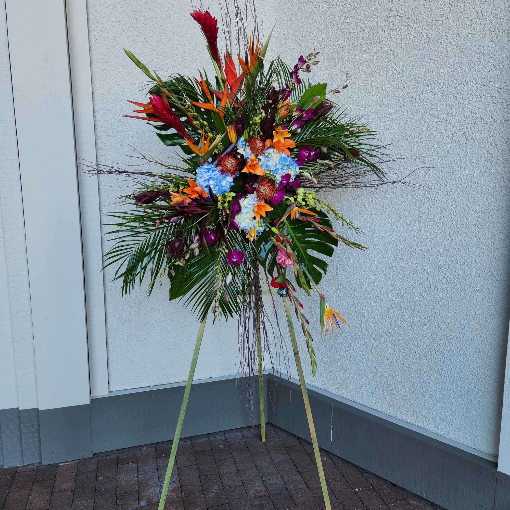 Tall tropical flower arrangement on a stand with bright mixed blooms