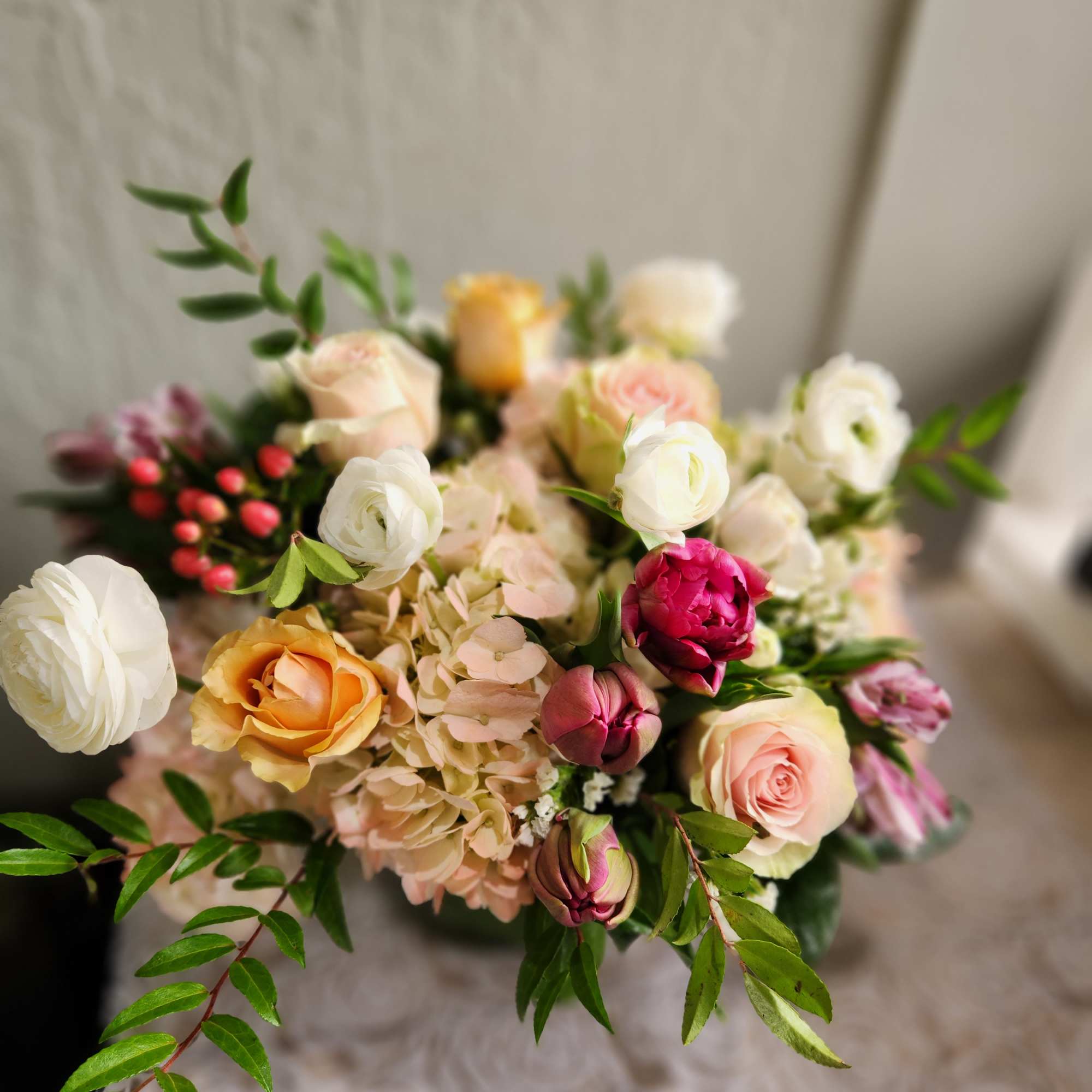 Hand-tied bouquet of roses, ranunculus, and hydrangea in soft pastel colors