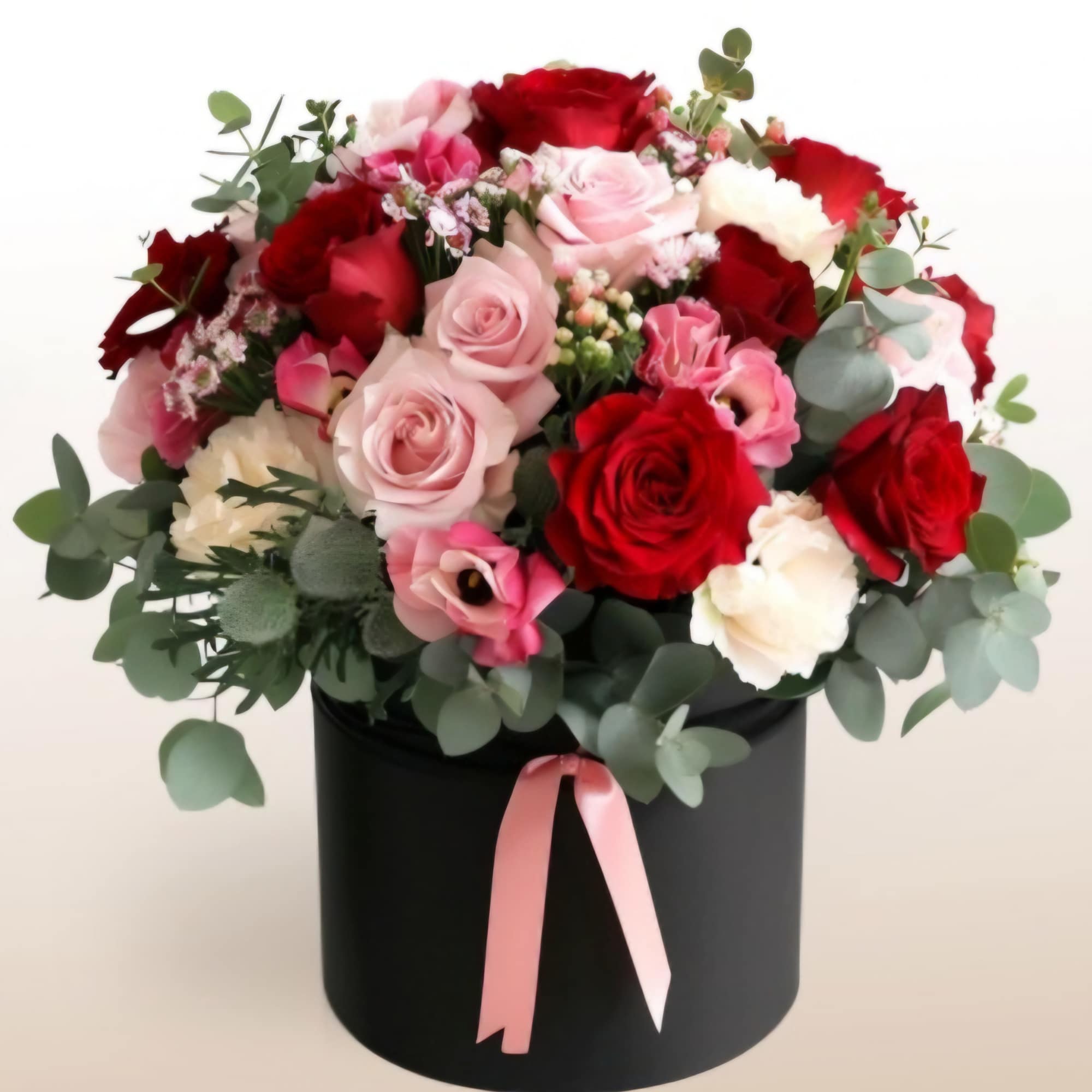 Bouquet of red and pink roses in a black hat box with a pink ribbon