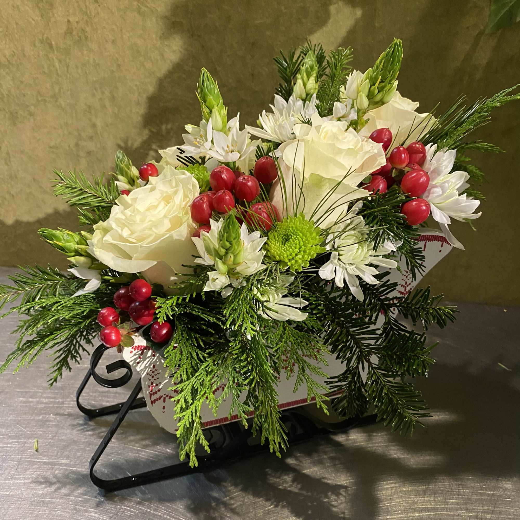 White floral arrangement with red berries in a decorative container