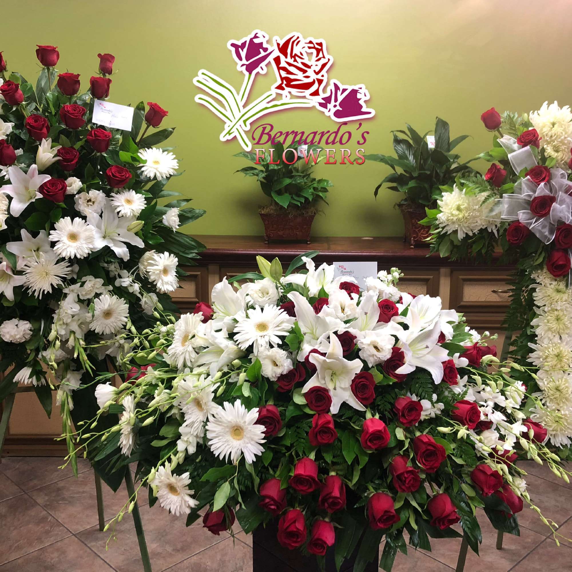 Large funeral floral sprays with red roses and white lilies and daisies