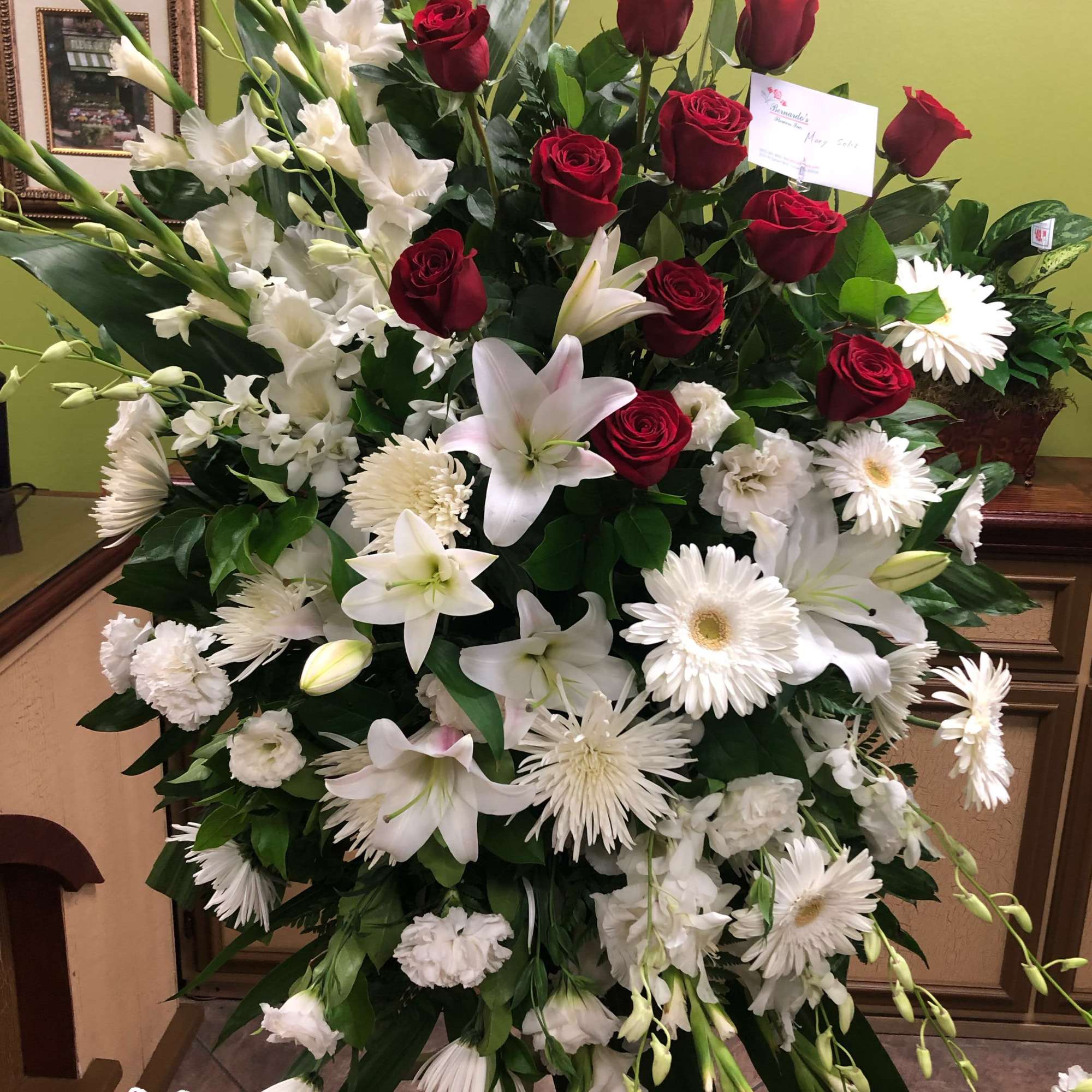 Large standing arrangement of red roses and white lilies with daisies