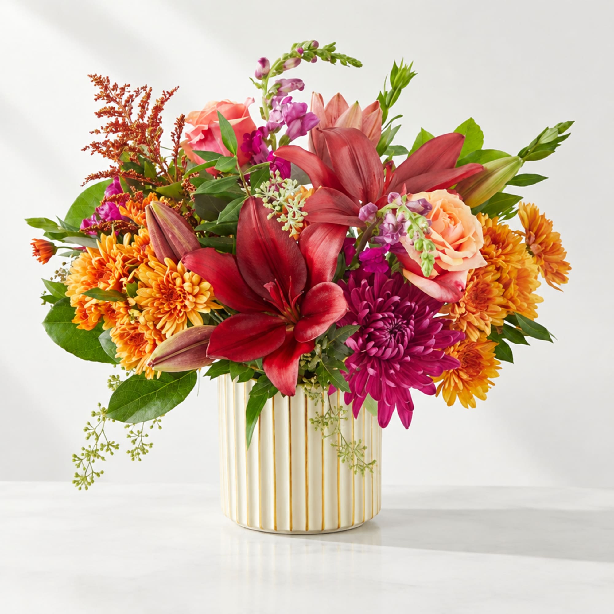 Colorful bouquet of lilies, chrysanthemums, and roses in a striped vase