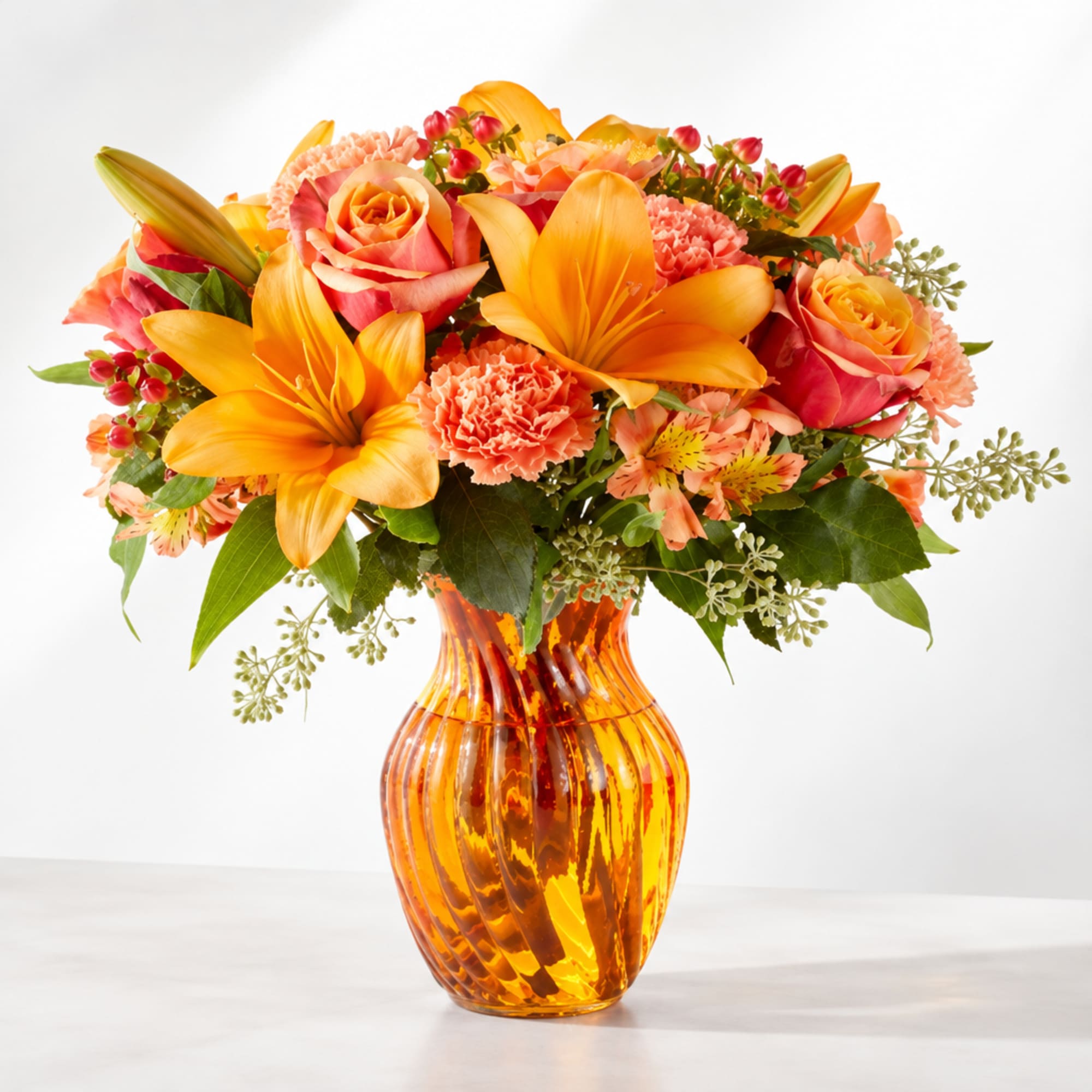 Orange and pink bouquet in an amber glass vase