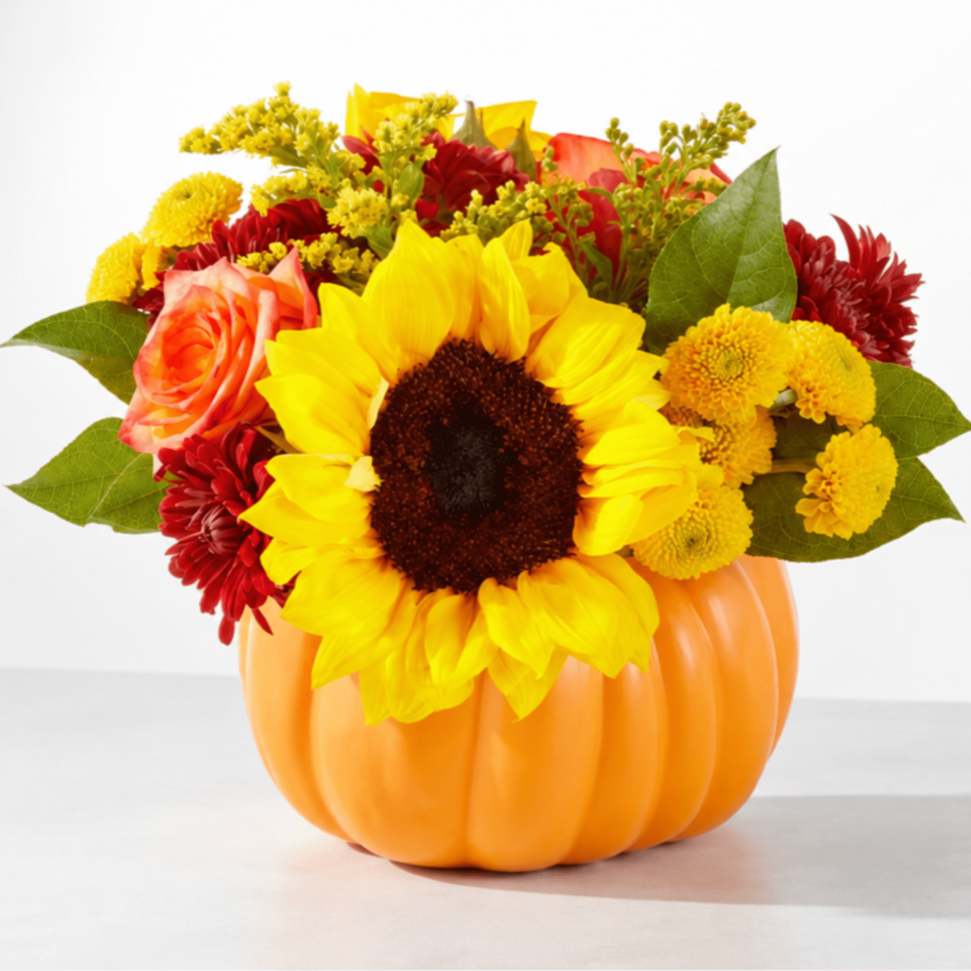 Sunflower and mixed flower arrangement in an orange pumpkin container